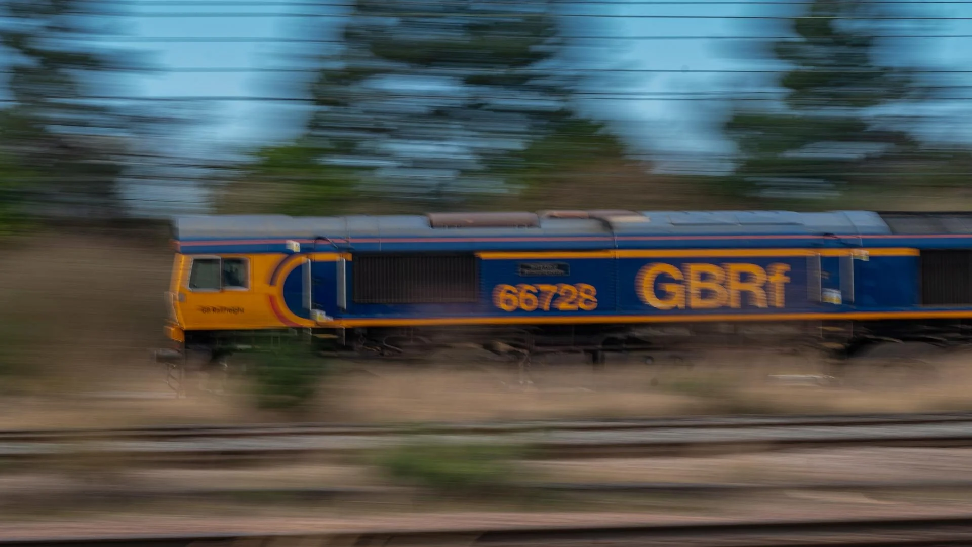 GB Railfreight locomotive speeding along railway tracks in a dynamic, blurred motion shot, symbolizing speed, power, and movement.