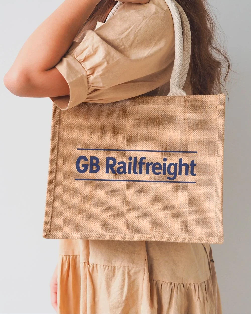 GB Railfreight logo in blue printed on a light brown tote bag, carried over the shoulder by a woman.