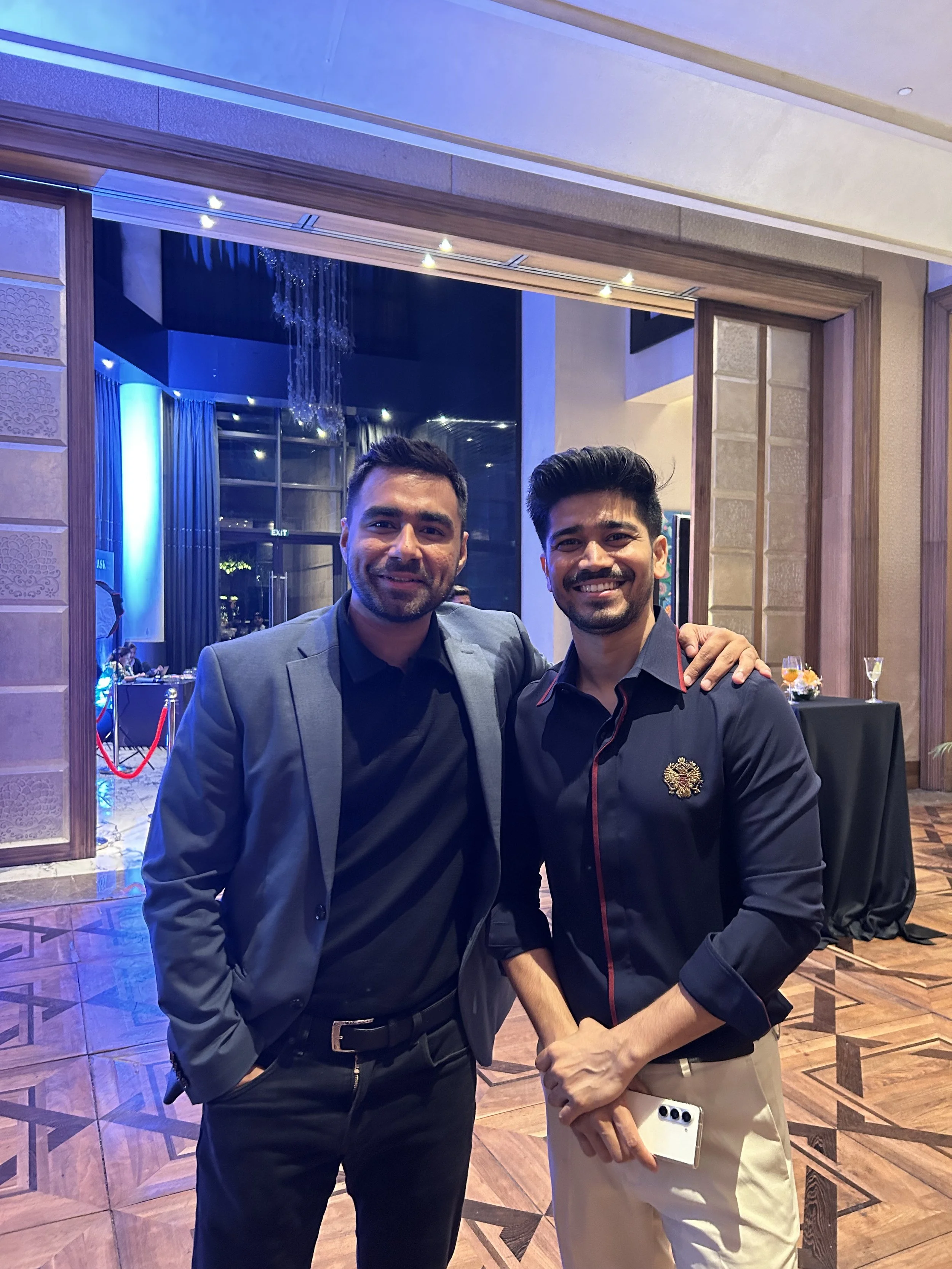 Two men dressed in formal attire at an indoor event, smiling for the camera.
