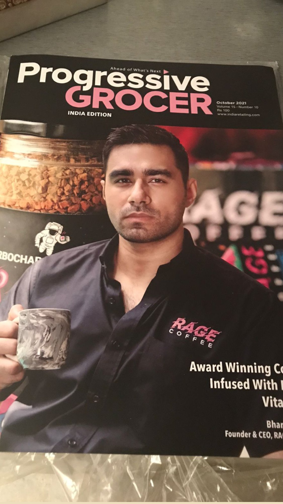 Cover of Progressive Grocer magazine featuring a man with short dark hair, wearing a black shirt with RAGE Coffee logo, holding a marble-patterned mug. The magazine is the India edition, October 2021.
