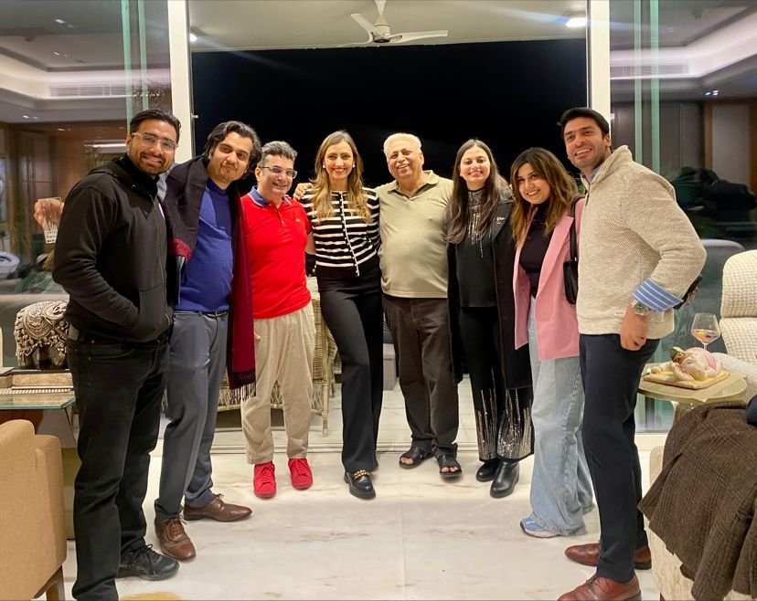 A group of eight people standing close together in a warmly lit indoor space at night, smiling at the camera.