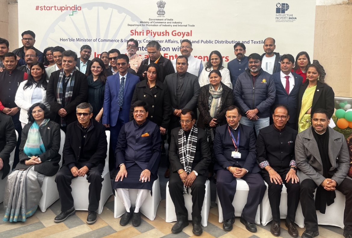 Group photo of people attending an official event in India, with a banner in the background displaying government logos and text about a conference with Shri Piyush Goyal, including men and women dressed in business and traditional attire, some seate