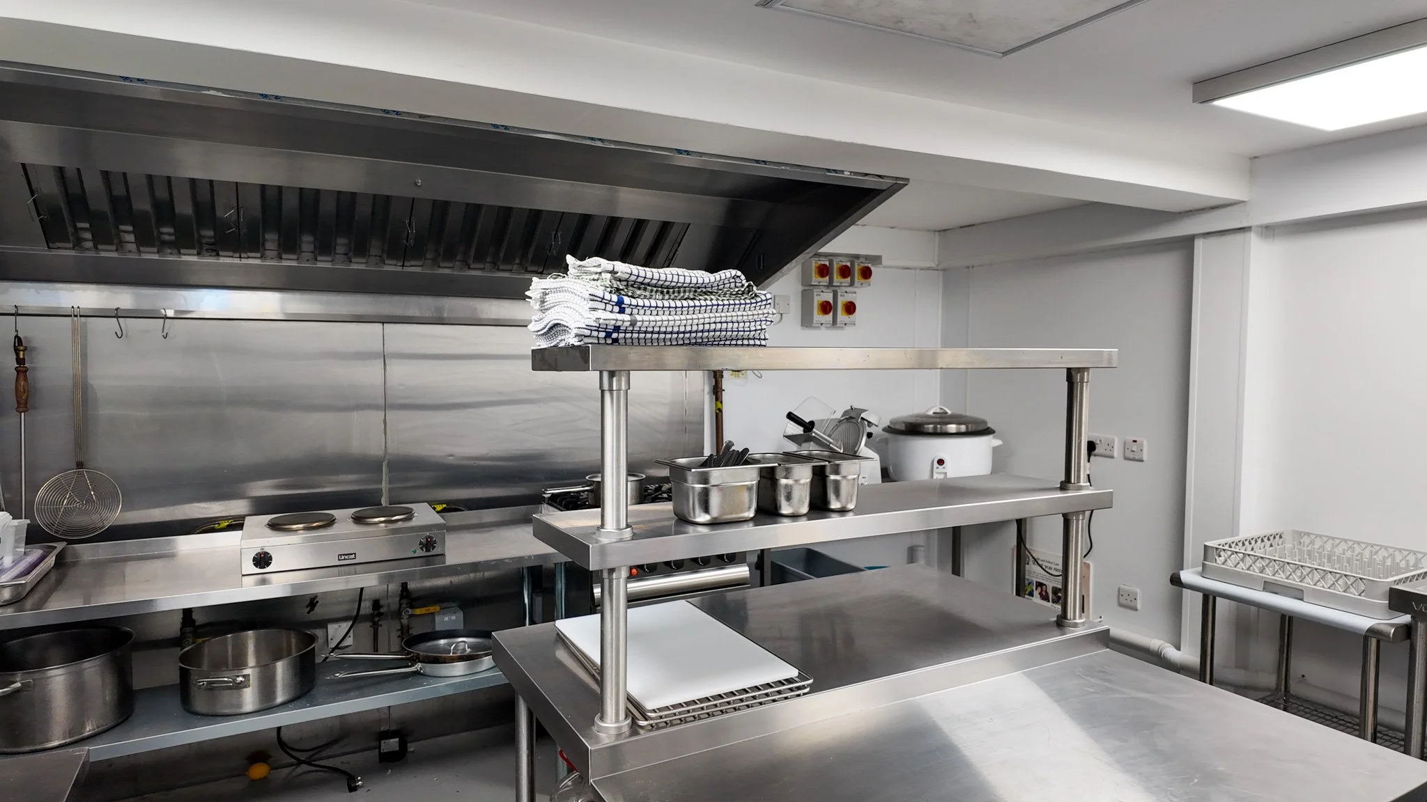Encore Kitchens commercial kitchen with stainless steel extraction canopy, three-phase power isolators and prep stations