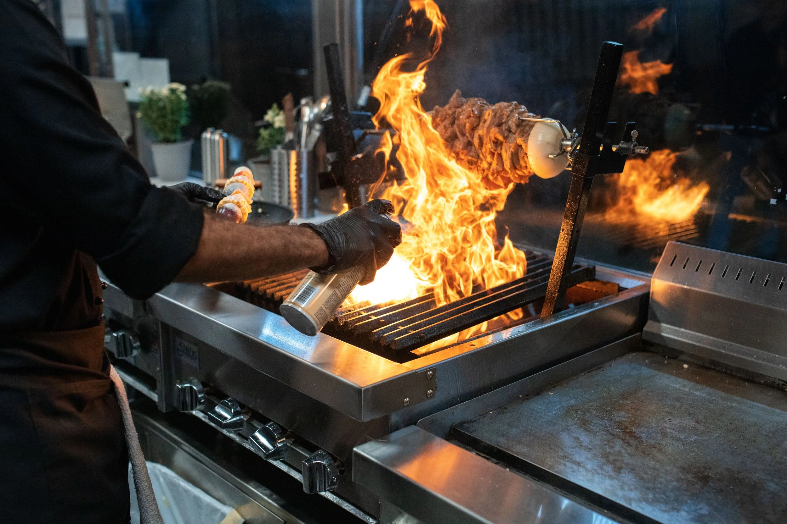 Chef cooking on an open flame grill in a commercial kitchen