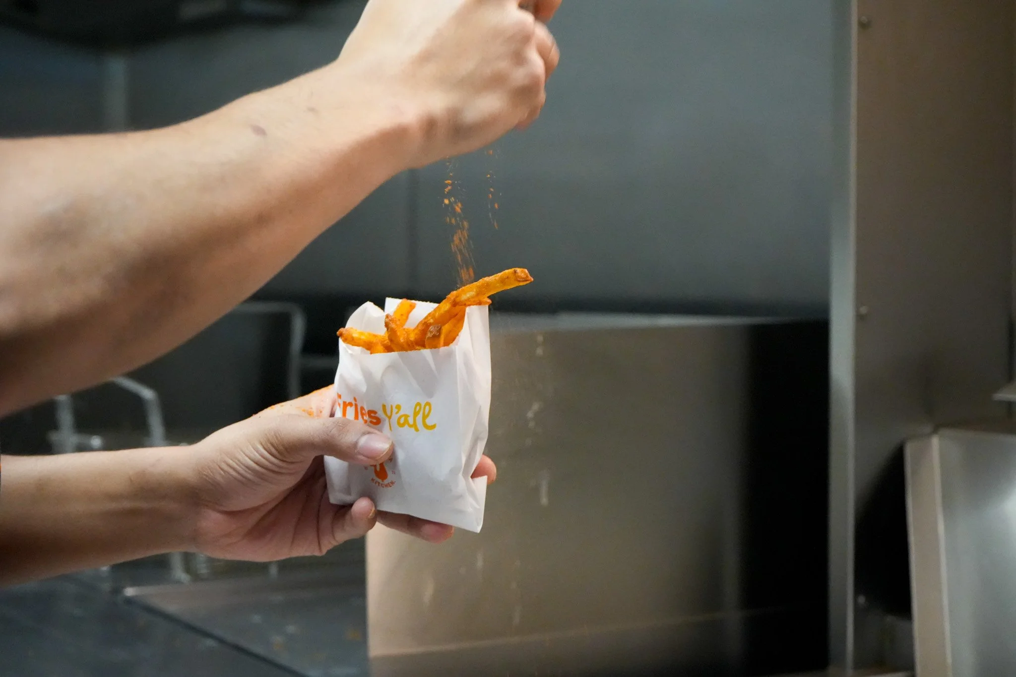 Sweet potato fries being seasoned in a takeaway bag at a London ghost kitchen, prepared by an Encore Kitchens tenant brand