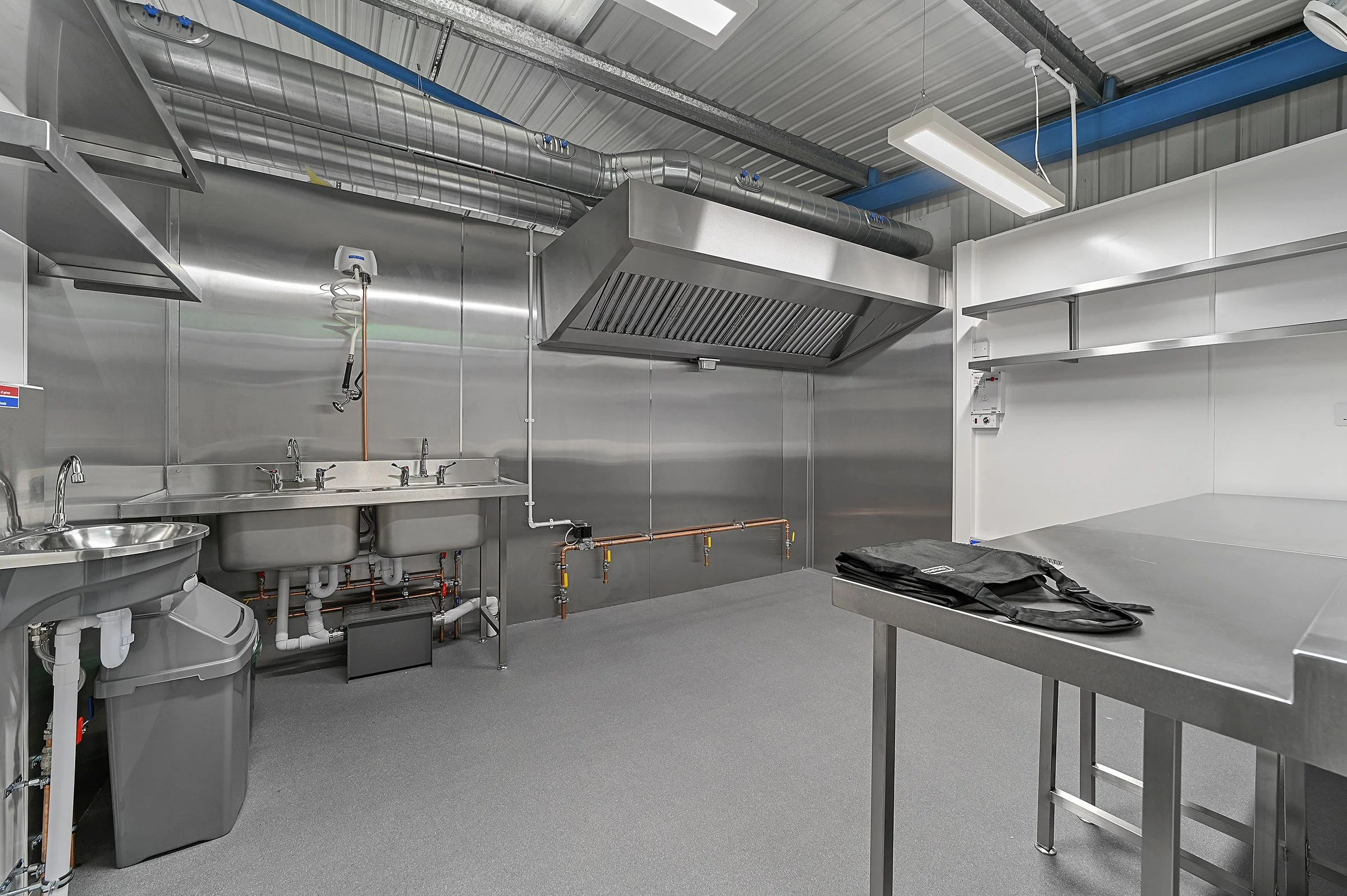 Fully fitted commercial kitchen at Encore Kitchens with stainless steel extraction canopy, gas connections, sinks, and prep space ready to trade.