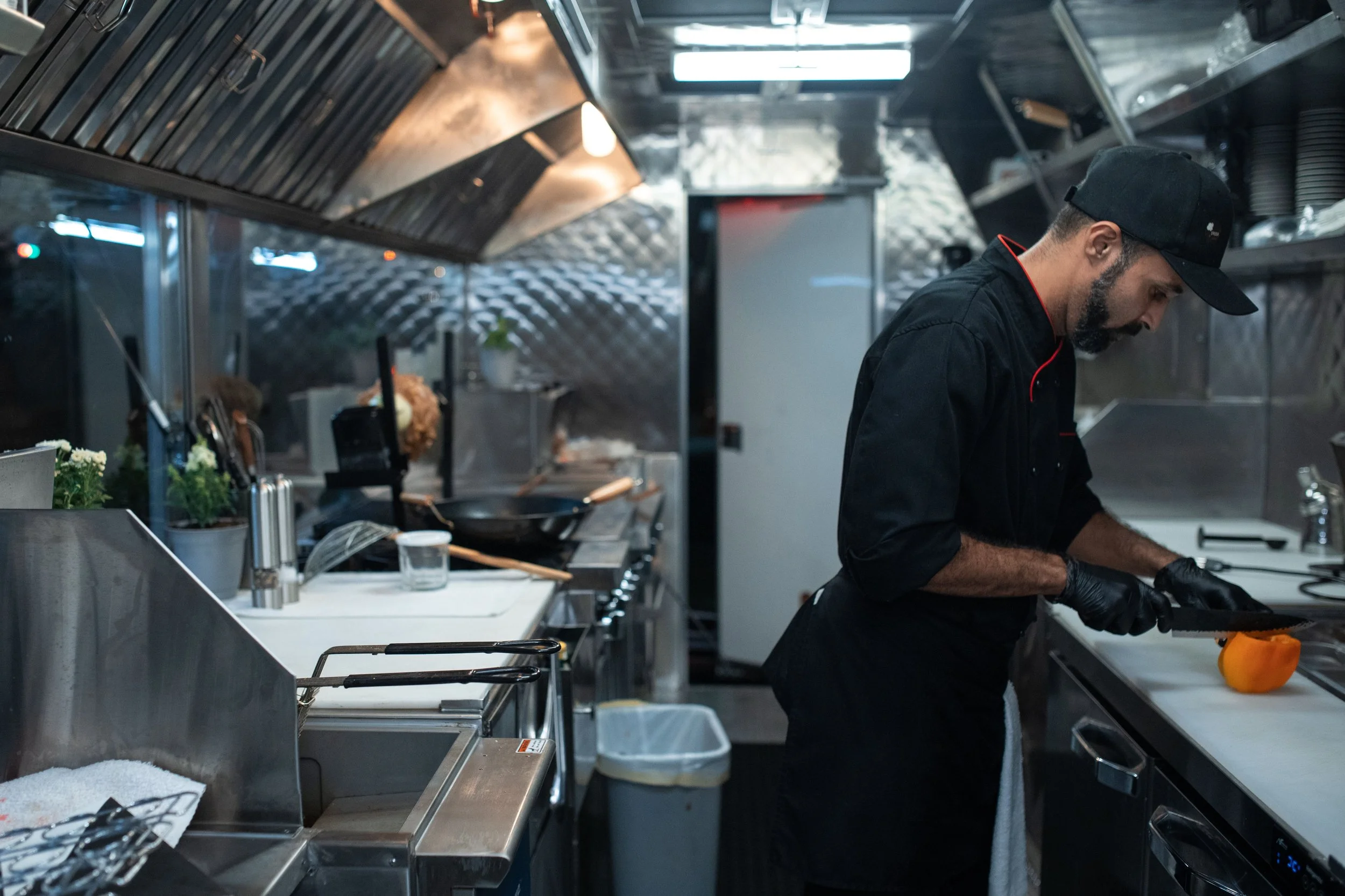 Chef working in a compact commercial kitchen fitted with stainless steel equipment and extraction
