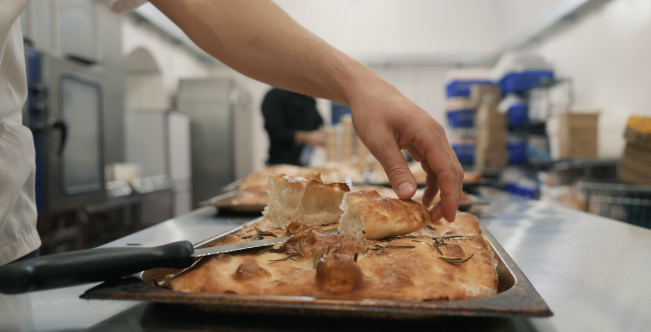 Freshly baked rosemary focaccia being sliced at an Encore Kitchens ghost kitchen in London