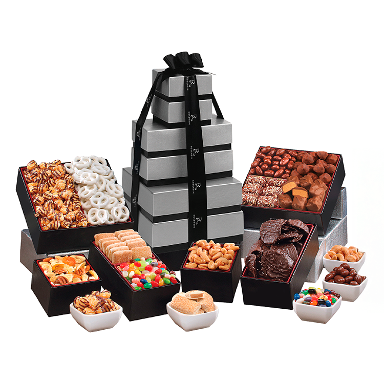 An elaborate gift box set with stacked gray boxes tied with a black ribbon, surrounded by various boxes and bowls of assorted chocolates and snacks.