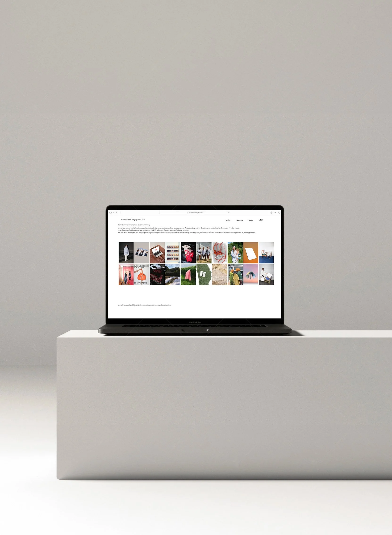 A laptop on a white pedestal displaying a webpage with a grid of various photos.
