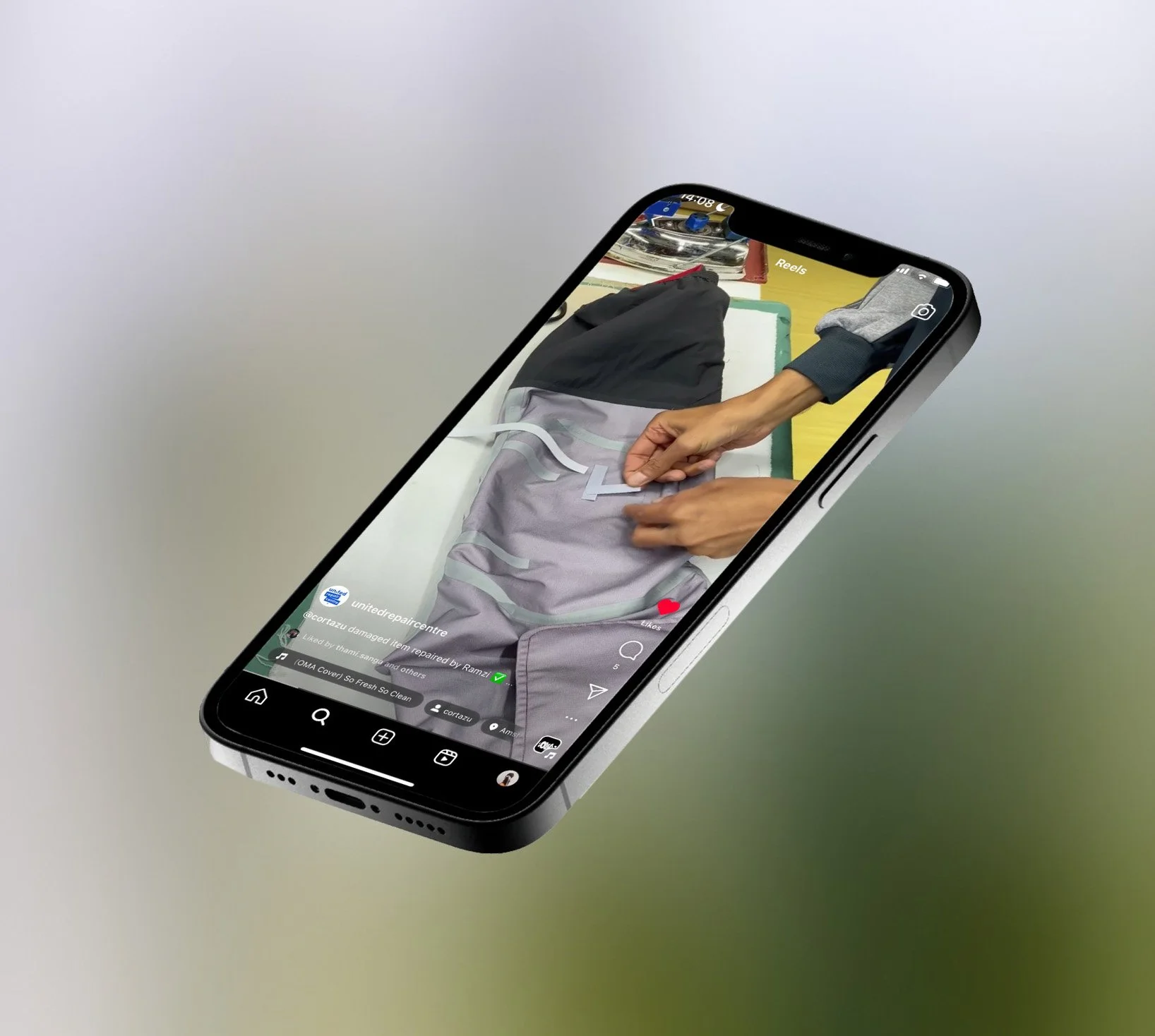 Close-up of a smartphone screen showing a video of hands repairing or assembling a gray and black clothing item on a white surface.