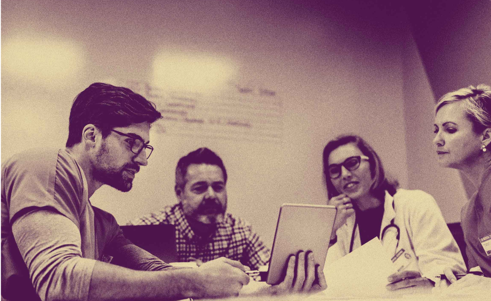 Four doctors huddles at a desk around an chart