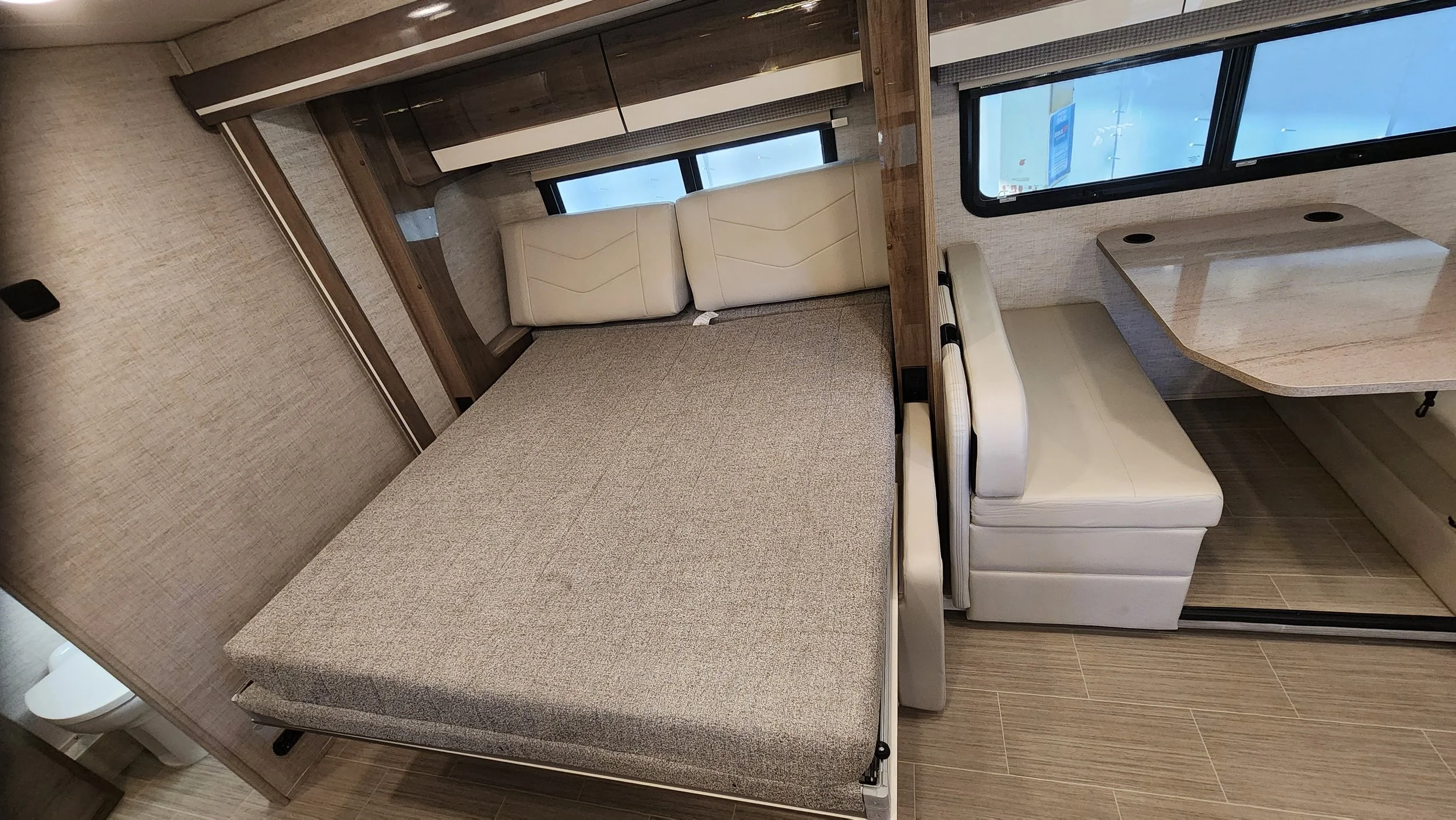 Inside a compact RV or camper with a bed, a small couch, a window, and a table.
