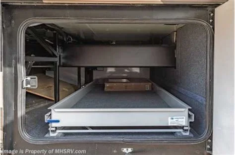 Empty storage compartment inside an RV with a slide-out tray for organization.