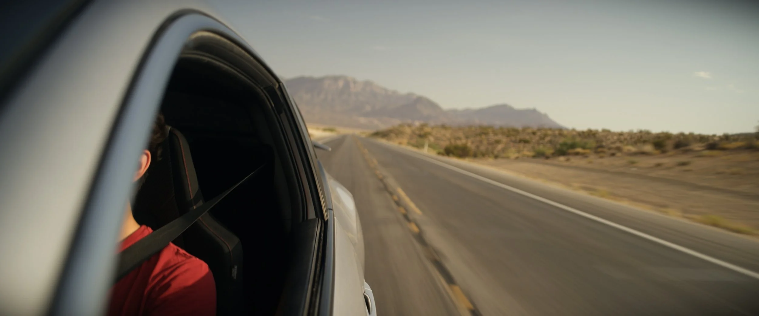 View from a car's side window on a highway in a desert landscape.