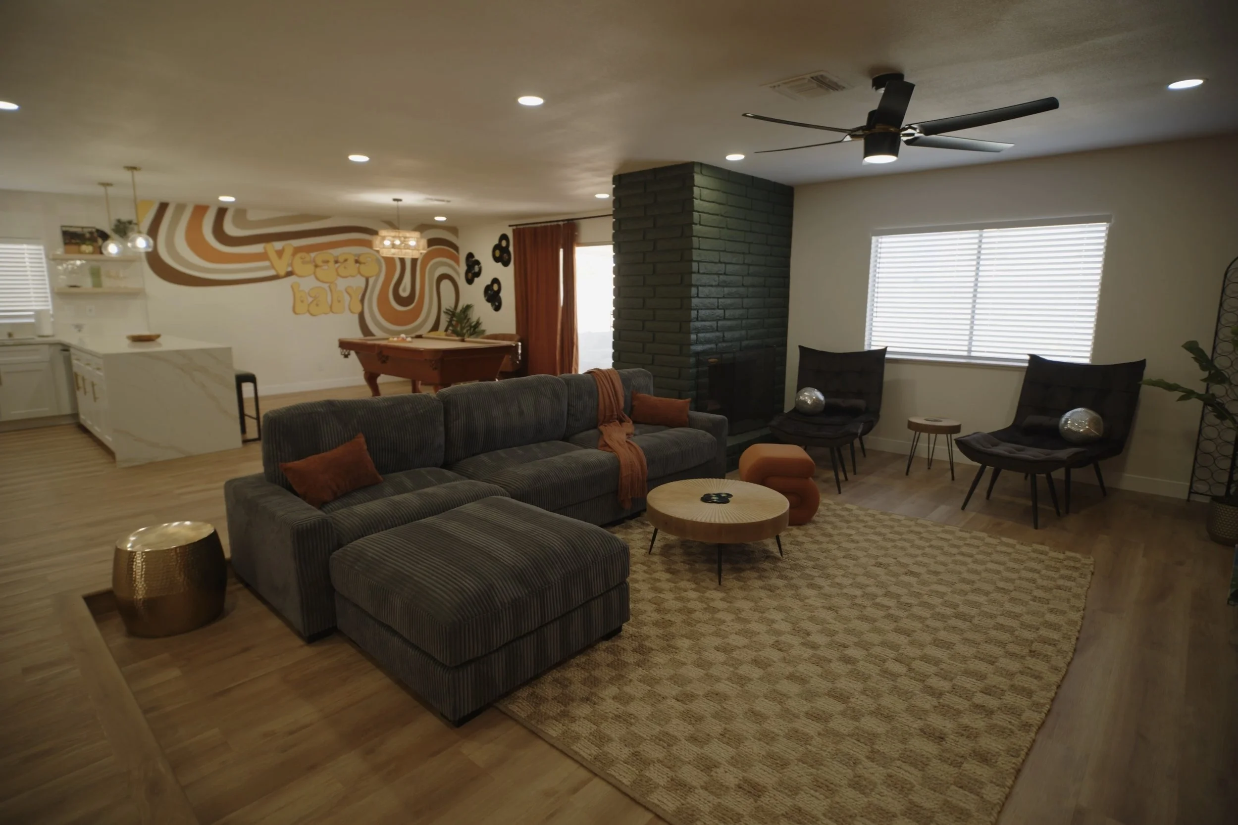 Modern living room with sectional sofa, mid-century decor, pool table, wall art, and ceiling fan. Real Estate videography.