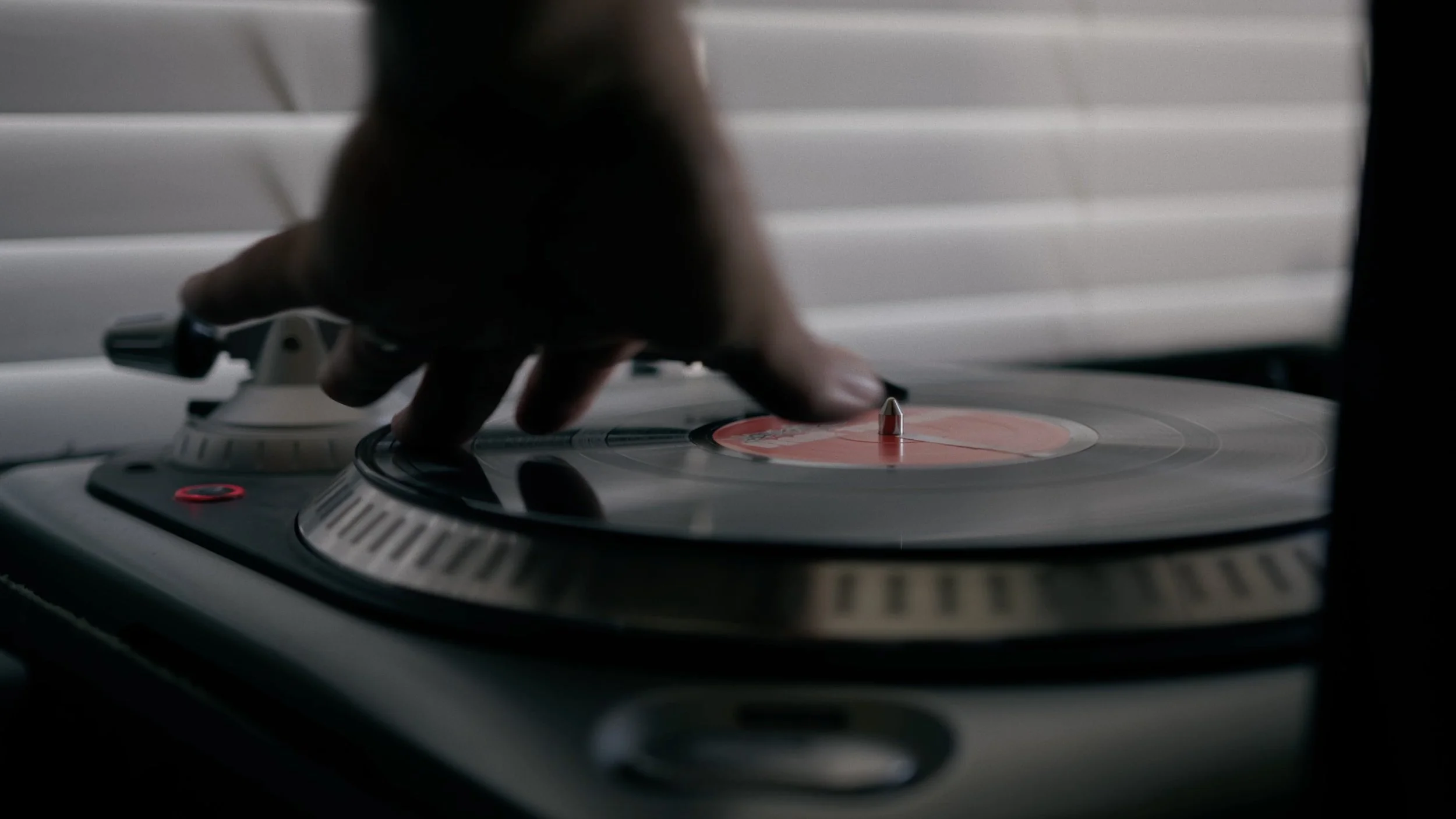Close-up of a hand adjusting a vinyl record on a turntable.