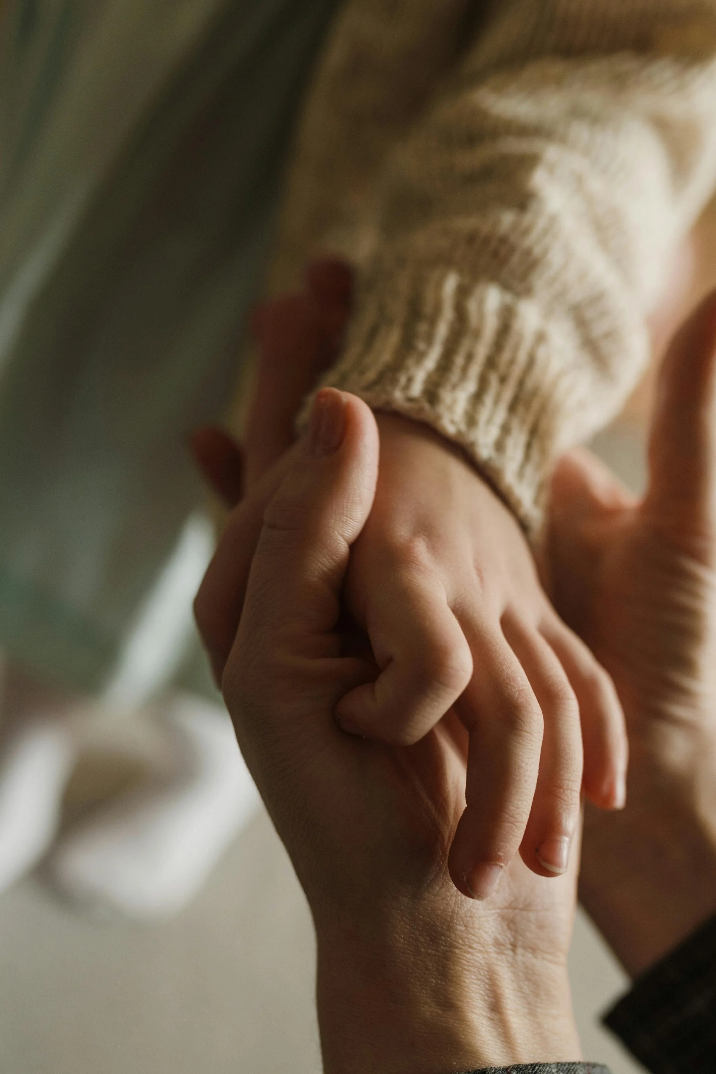 A close-up of an adult and child holding hands.