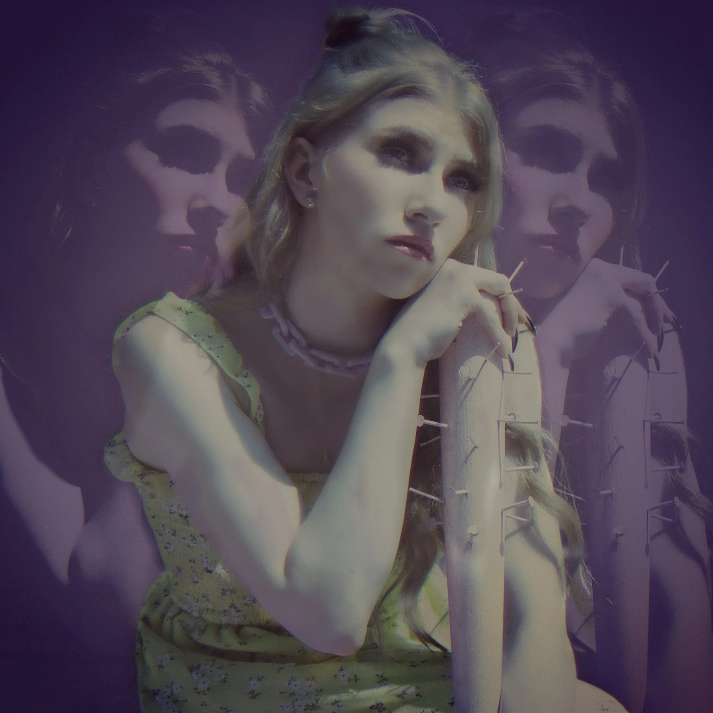 A woman with blonde hair and makeup, wearing a yellow dress with floral pattern, sits with her chin resting on her hand in front of a purple background. The background features a projected mirrored image of her.