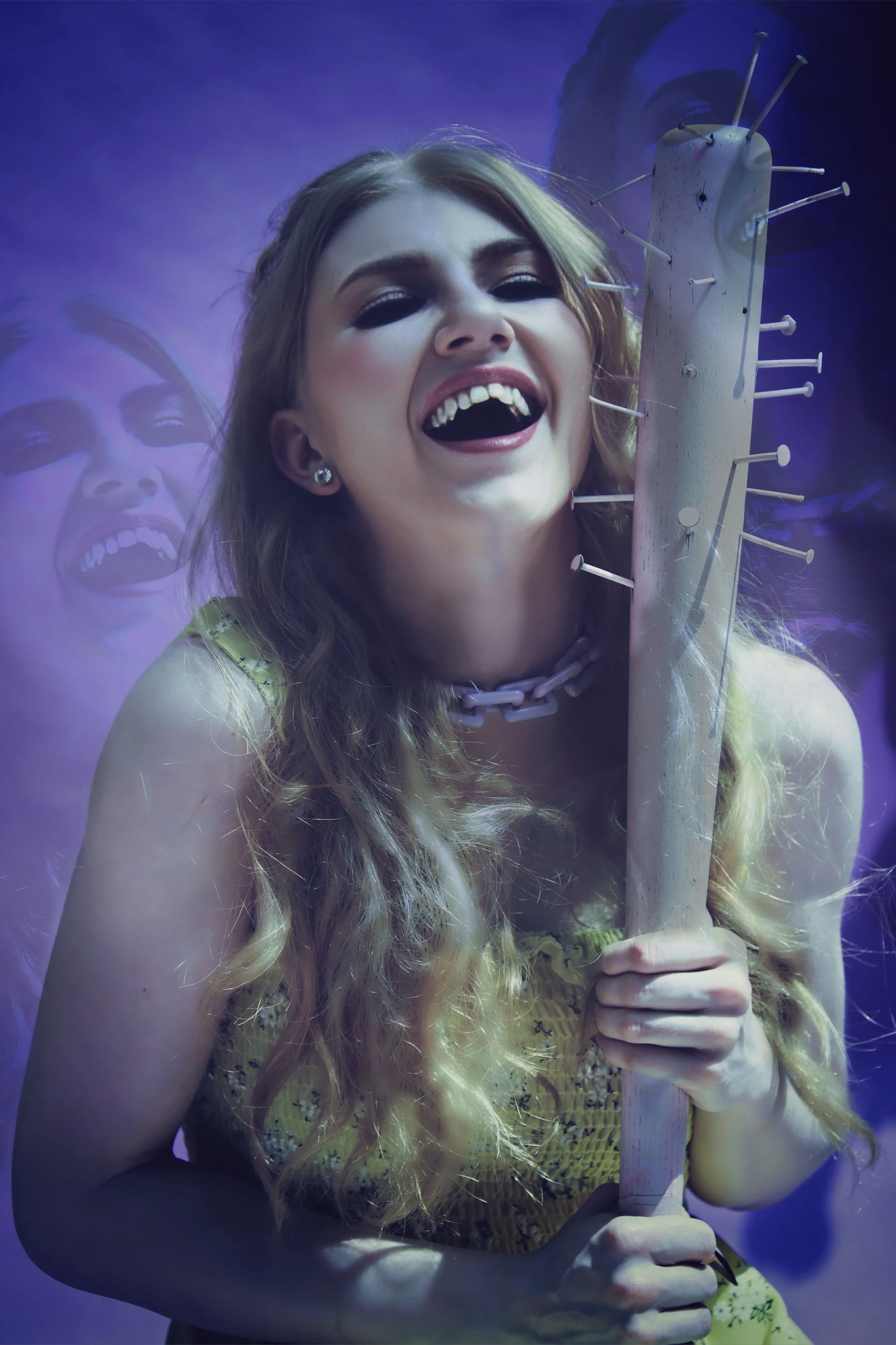 A young woman with long, wavy blonde hair holding a large nail-studded wooden plank, smiling and looking joyful. She is wearing a yellow dress, a gray chain necklace, and earrings, with a purple and blue background featuring a faint reflection of her face.