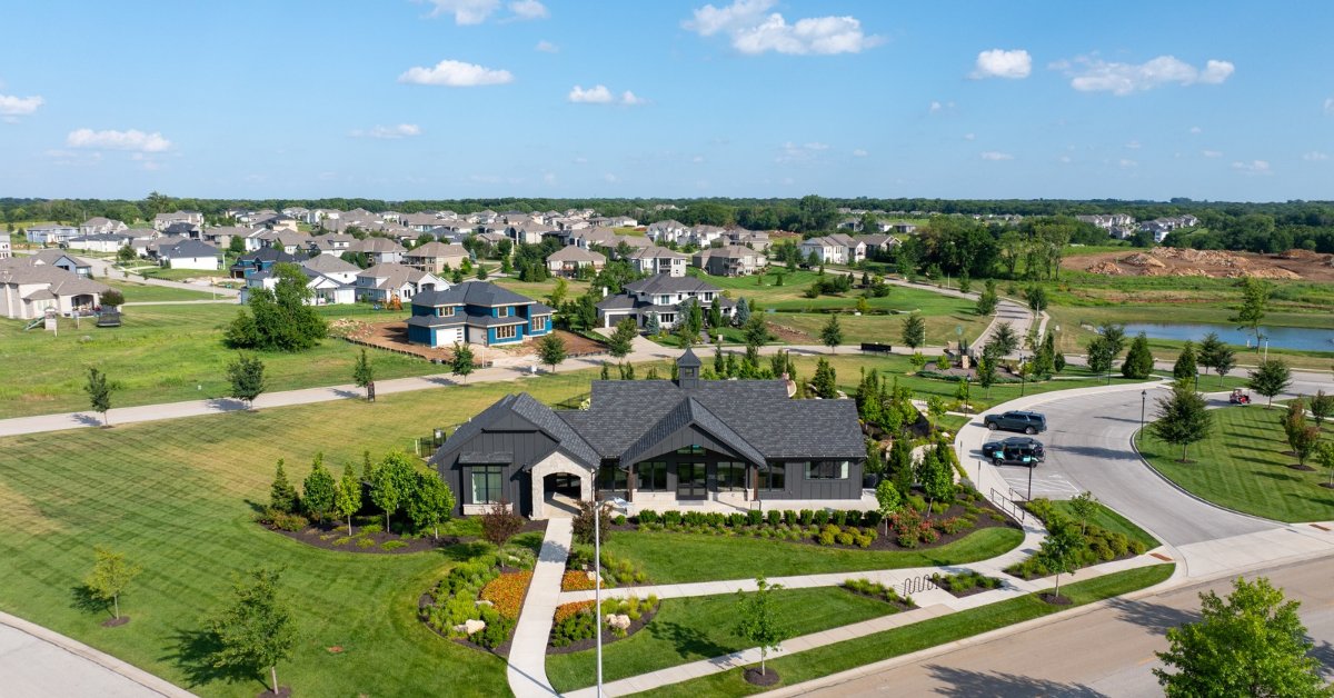 Aerial view of a curving residential street lined with two-story homes, backed by mature woods in South Overland Park