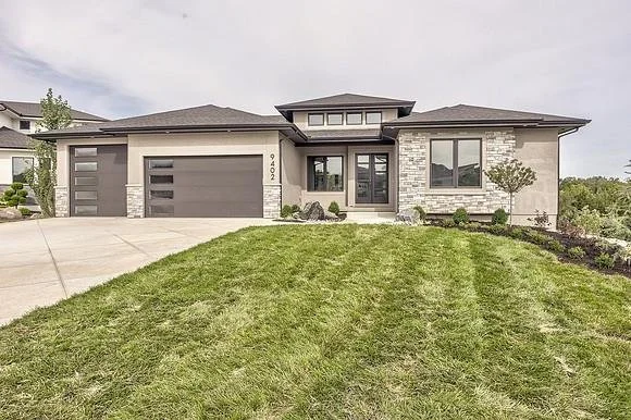 Newly built modern prairie-style ranch home with stone and stucco exterior and a three-car garage, an example of custom home construction