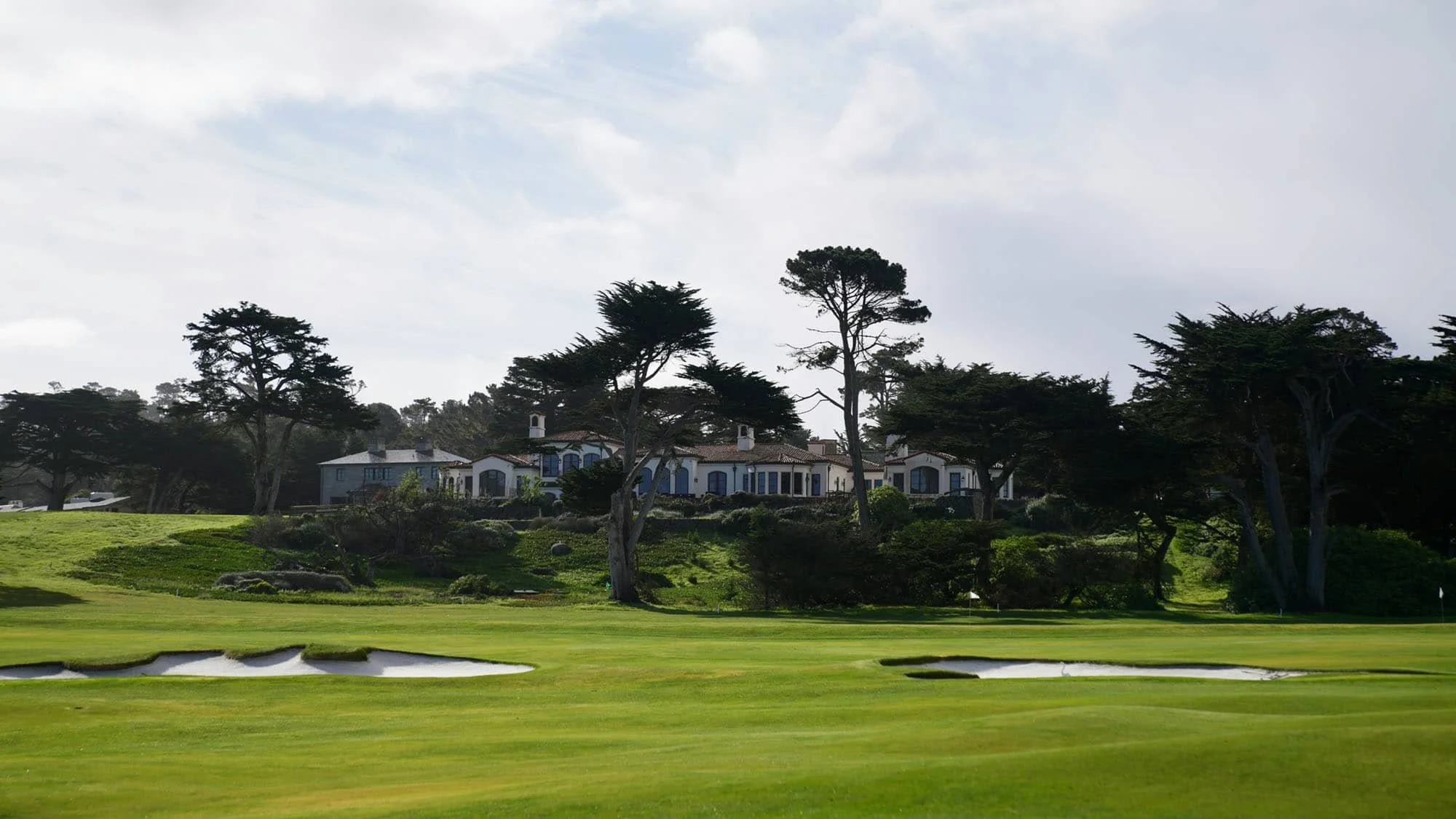 Elegant clubhouse nestled among trees overlooking the fairway at a private golf course.