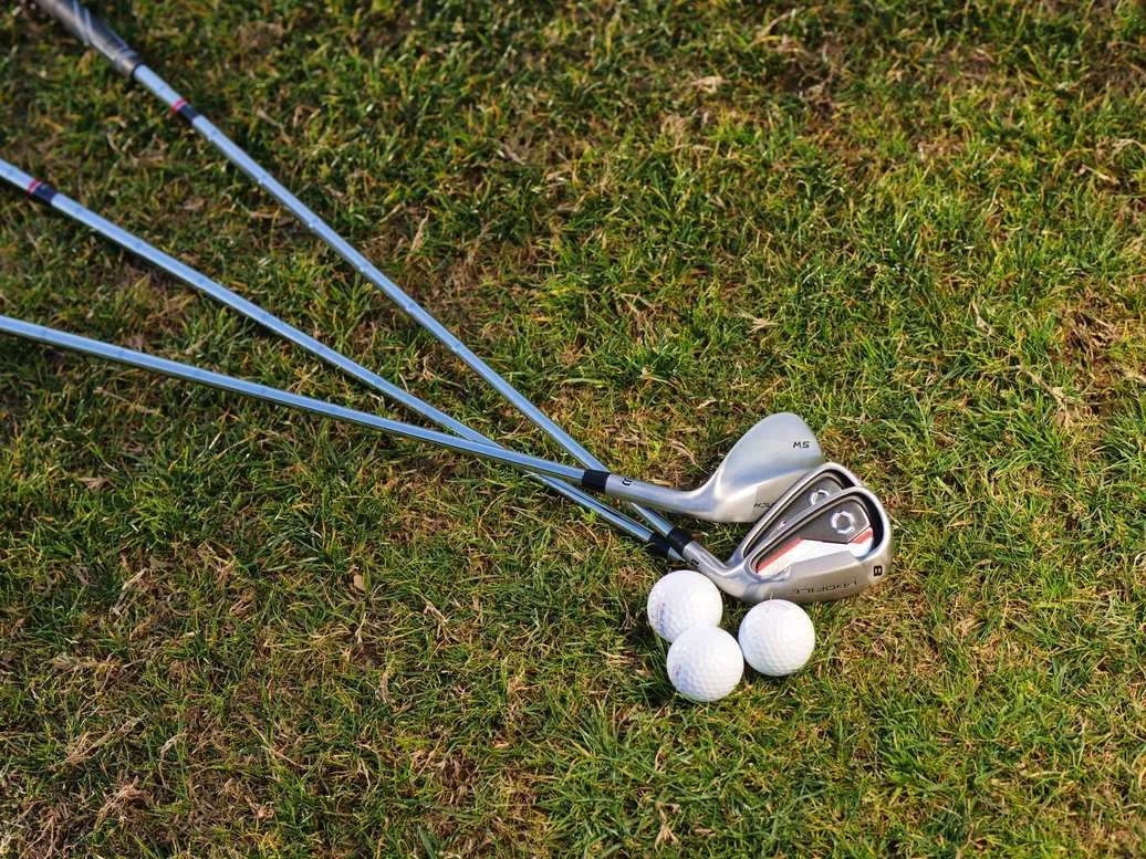 Golf irons and three white golf balls resting on the grass, ready for a round in private golf communities.