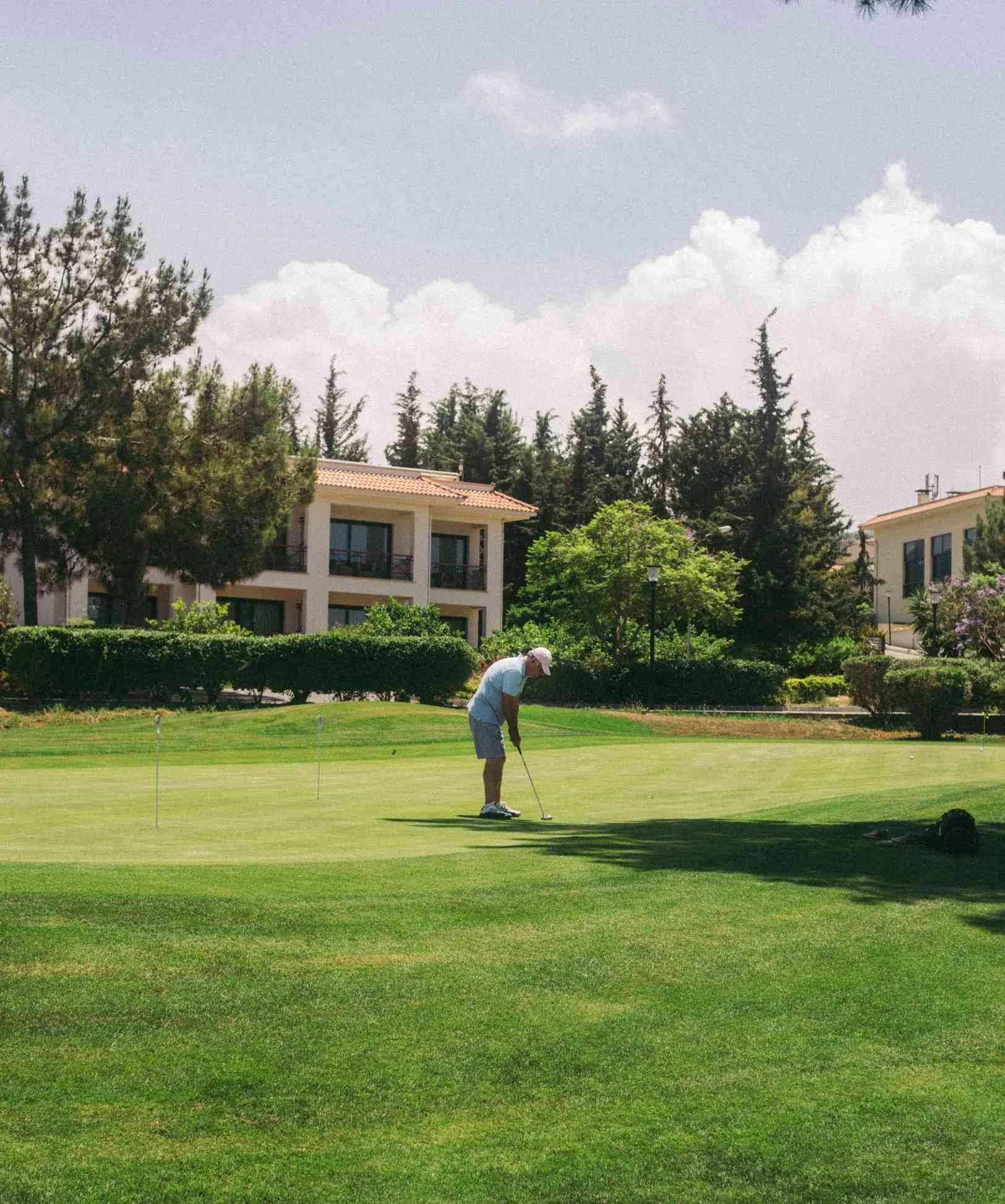Golfer putting on a green surrounded by luxury homes and mature trees in a Kansas City golf course community.