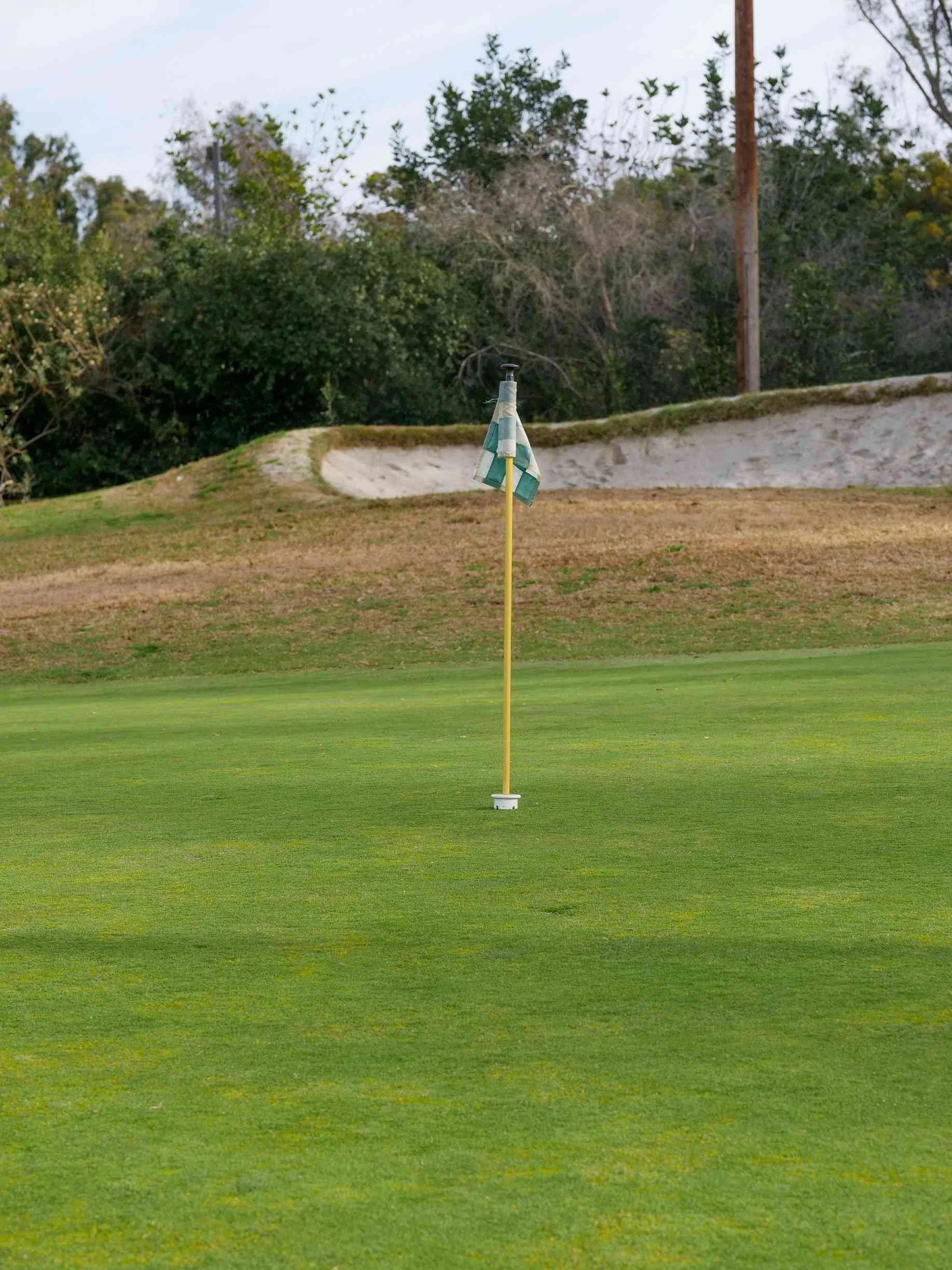 Yellow flagstick with a checkered flag on a putting green in private golf communities in Kansas City.