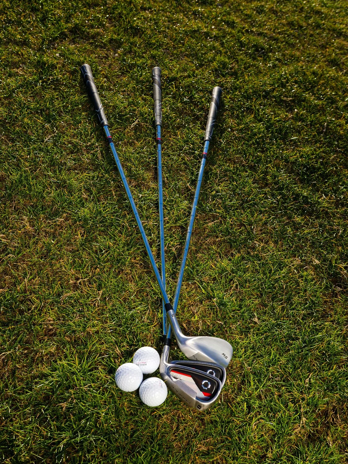 Golf clubs and balls resting on the grass at a private golf course in Kansas City.