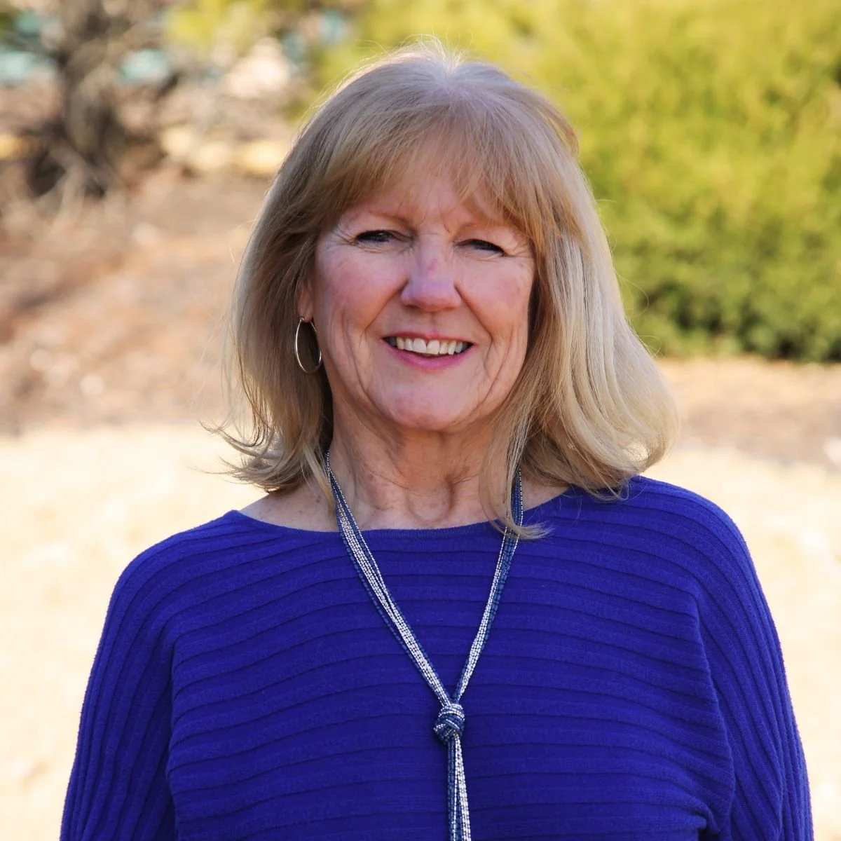 A woman standing outside, smiling at the camera.