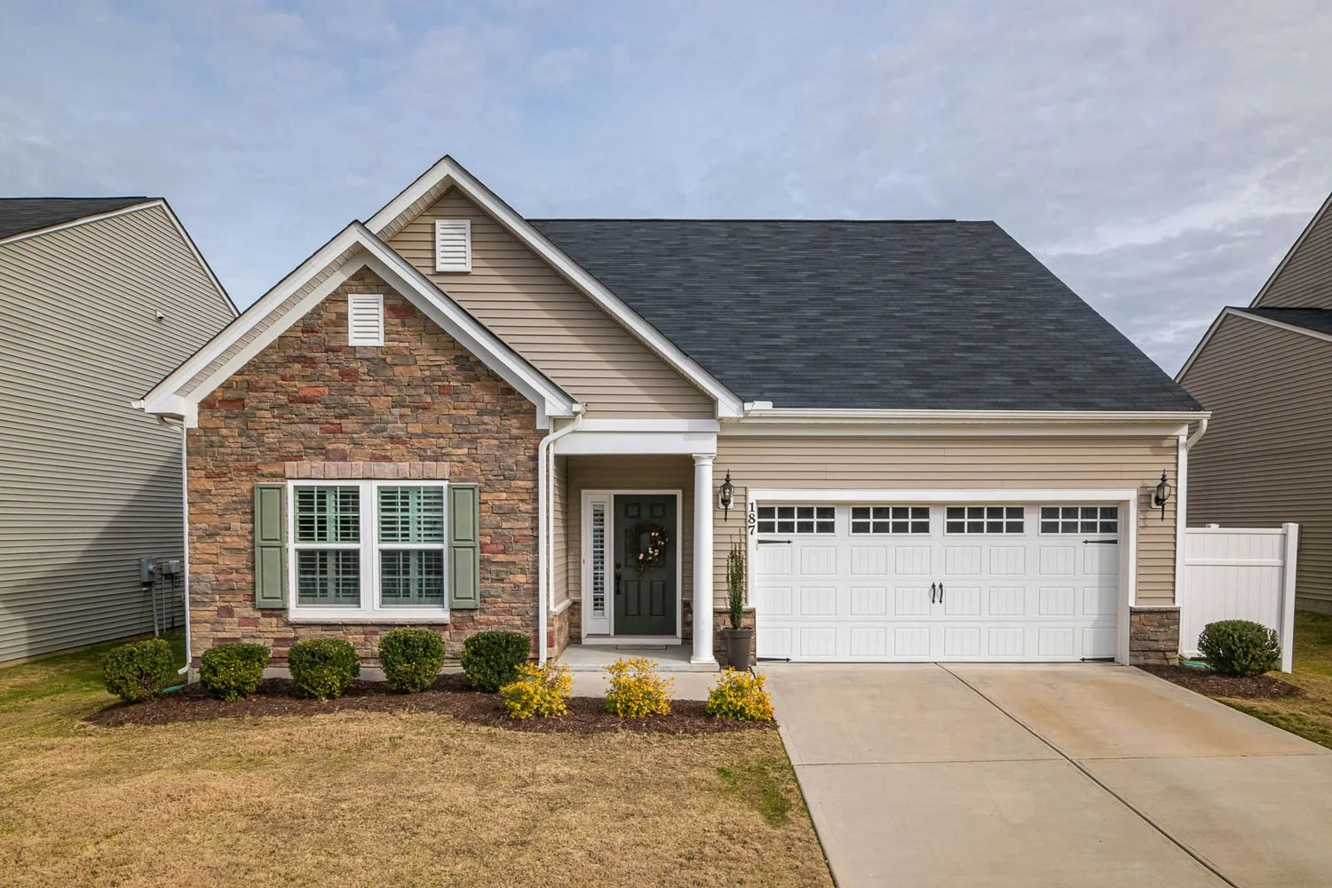 Single-story home with stone and beige siding, a covered entry, and a two-car garage