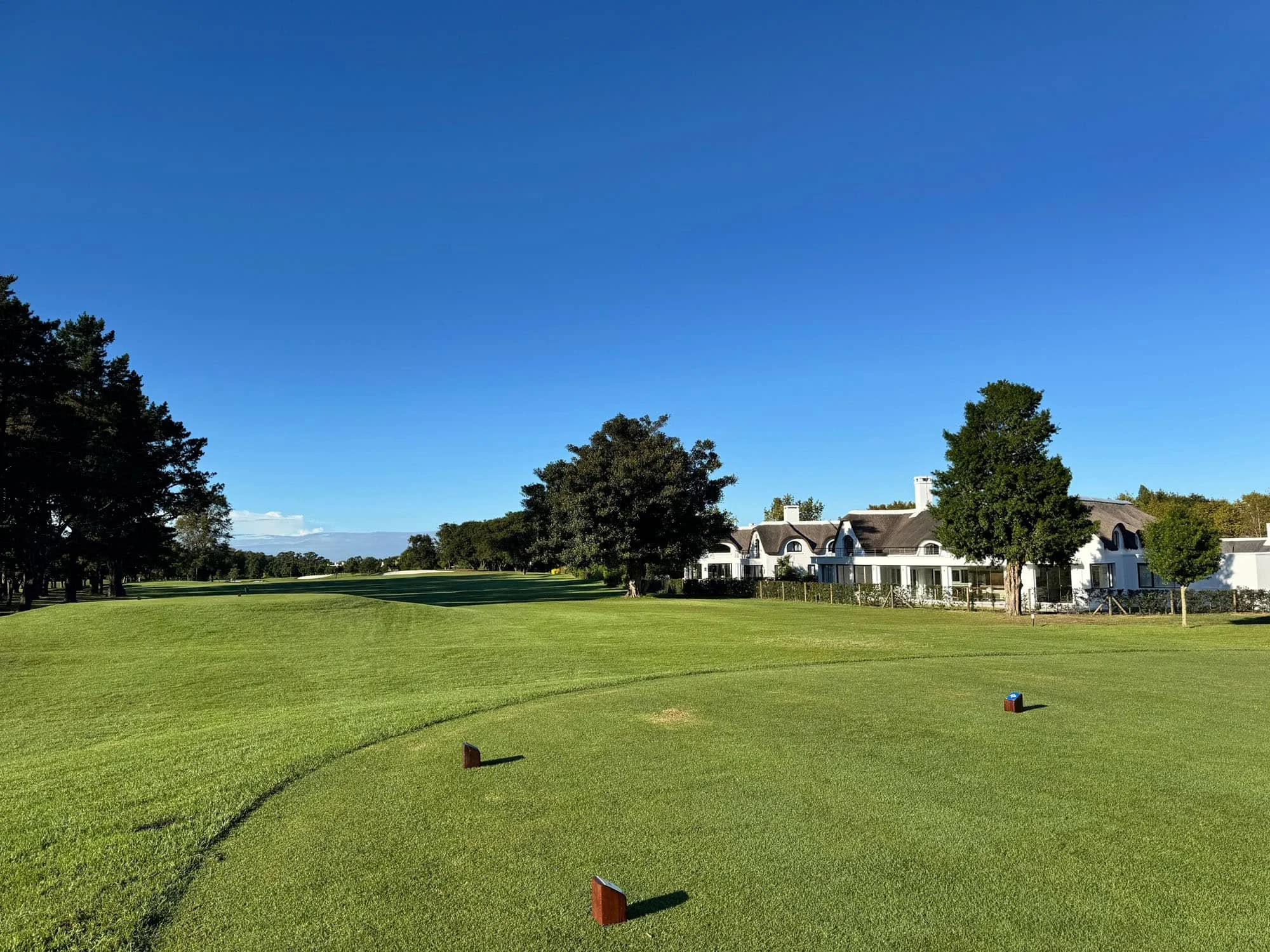 Golf course clubhouse surrounded by mature trees in a private golf community neighborhood.