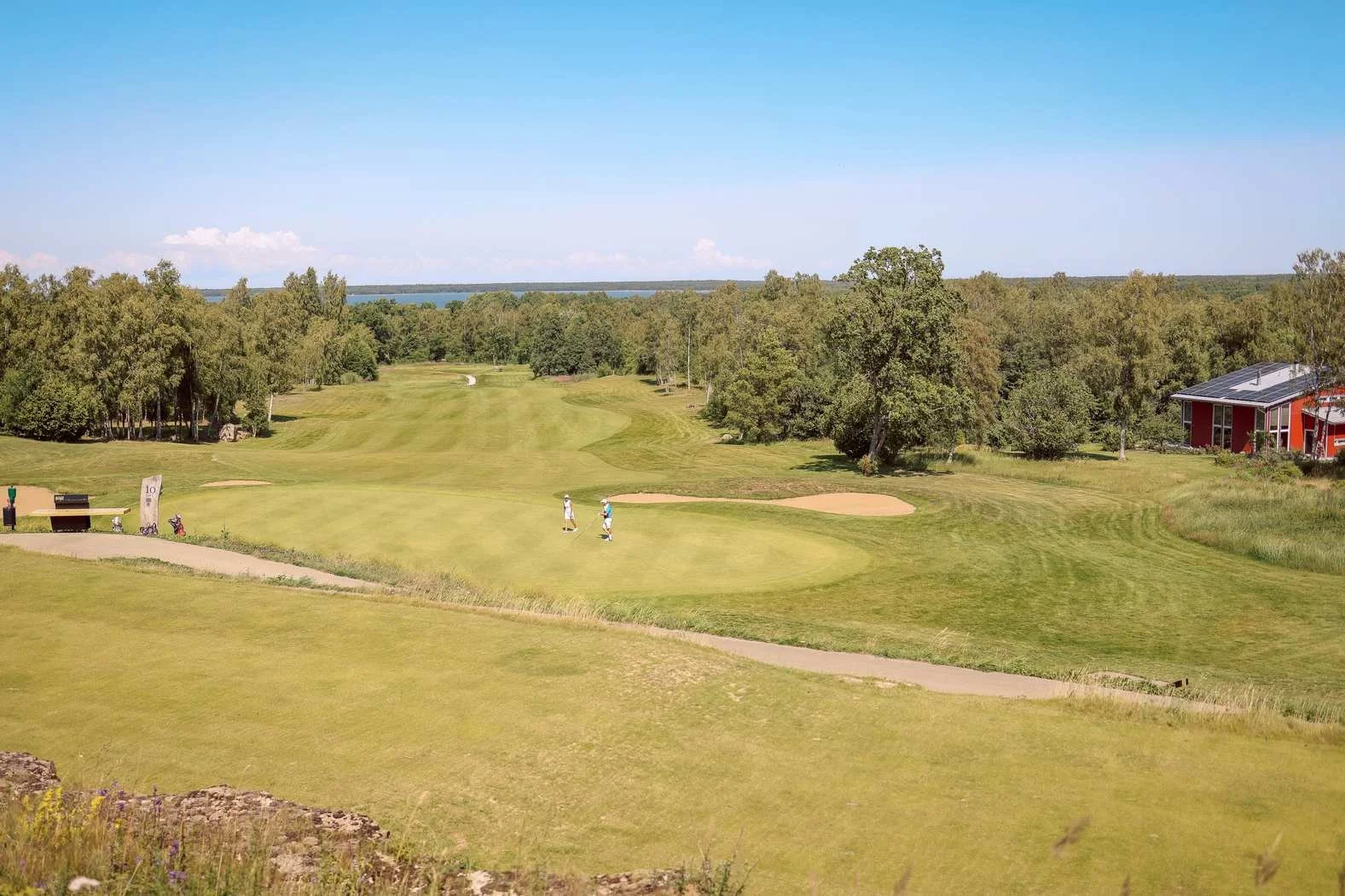 Sunny putting green, sand bunkers, and tree-lined fairway at one of Kansas City's private golf communities.