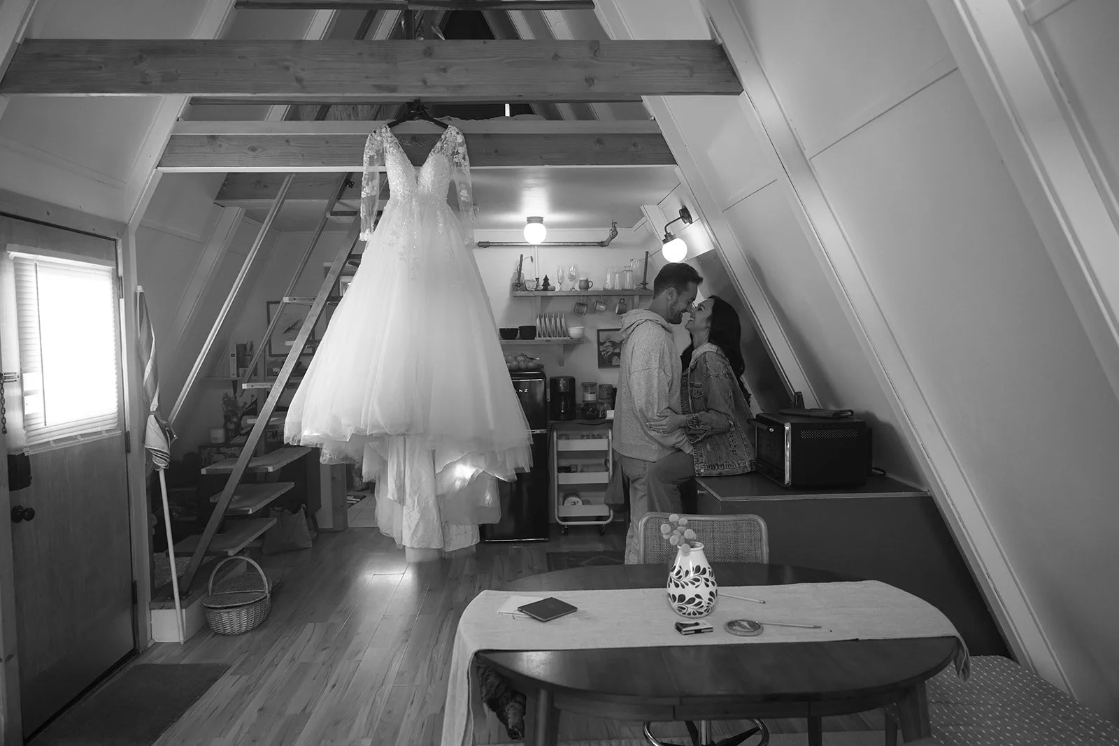 a couple in a A-framed Cabin in Yosemite with their wedding dress hanging from the rafters