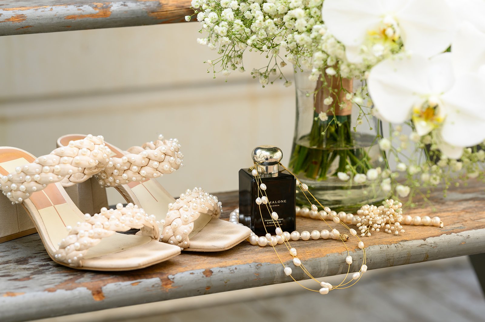 a photos of the brides wedding details including her shoes, jewelry, perfume, and flowers
