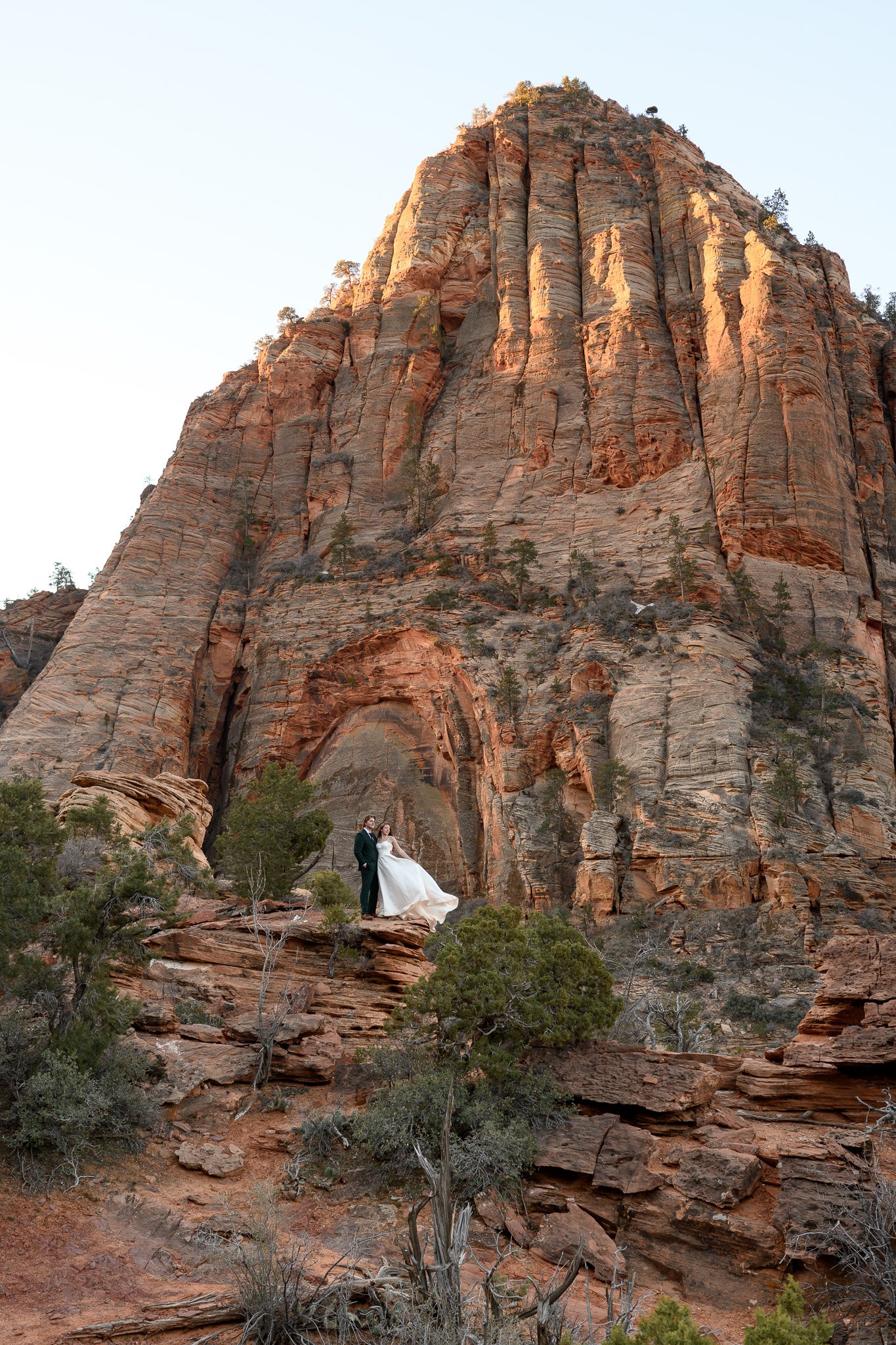 a wedding in Zion National Park with the bride and groom standing in front of a red mountain