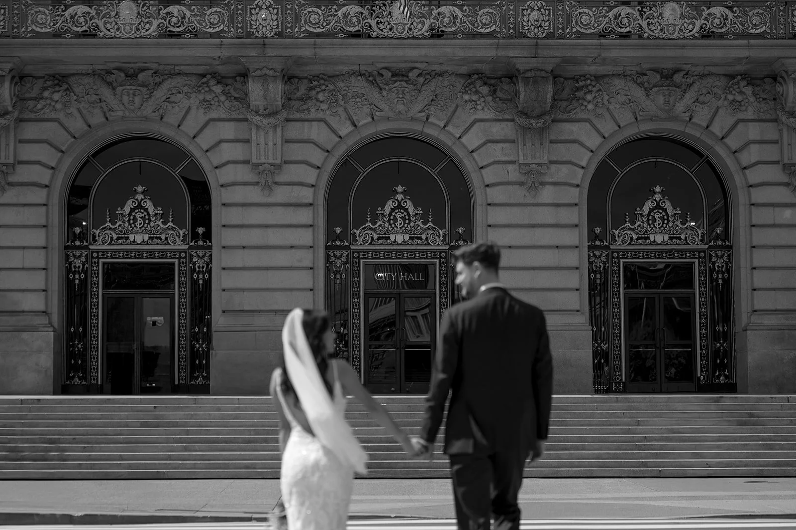 a bride and groom walking into City Hall