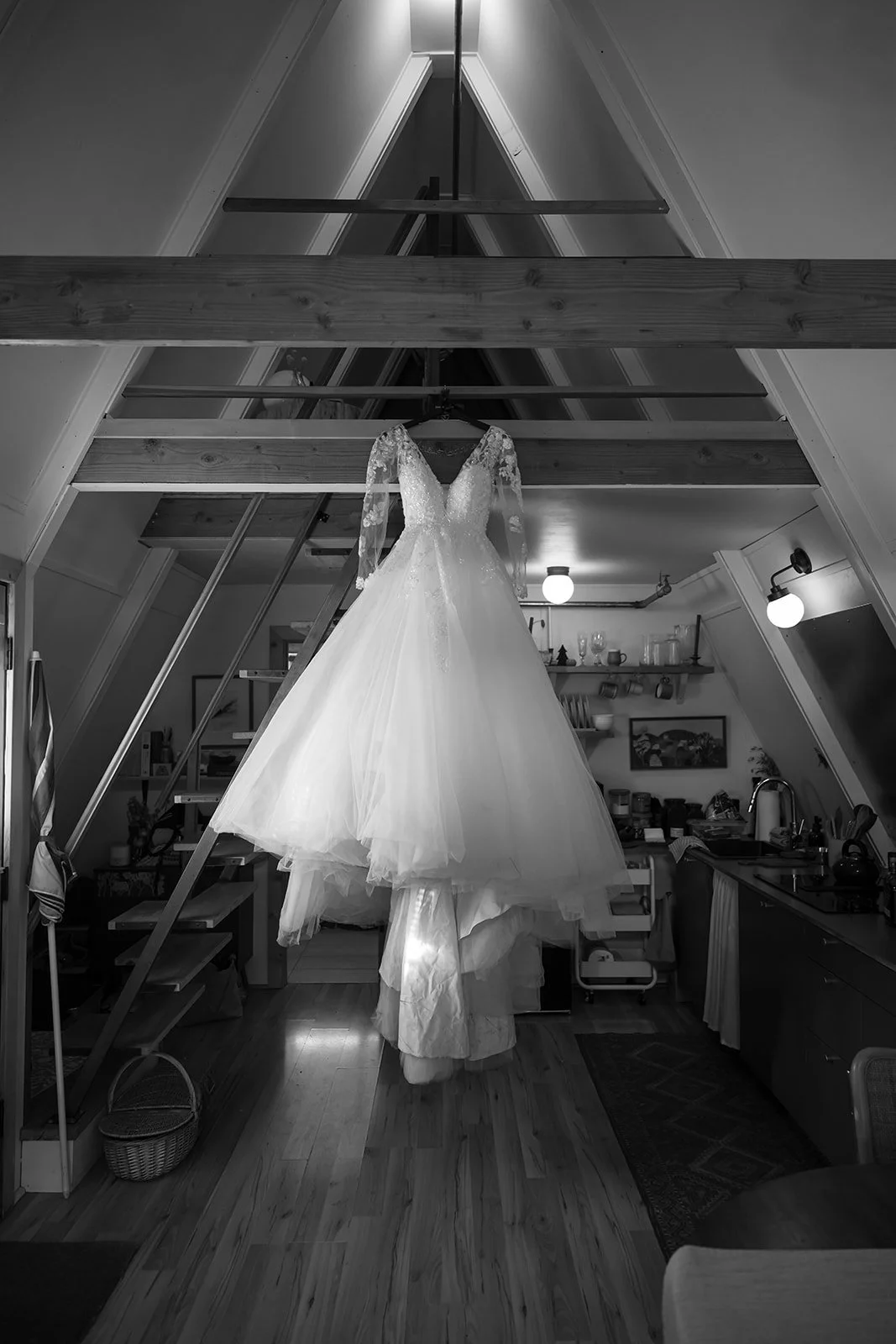 a wedding dress hanging from the rafters in an A-framed cabin