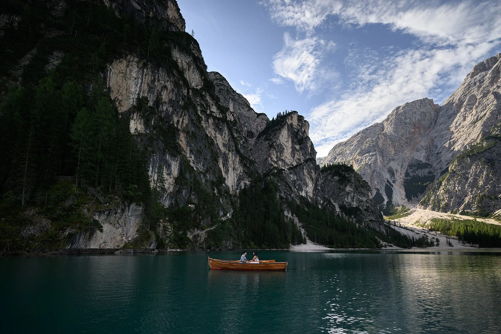 a photo of a bride and groom in a rowboat on lago di braies in the dolomites