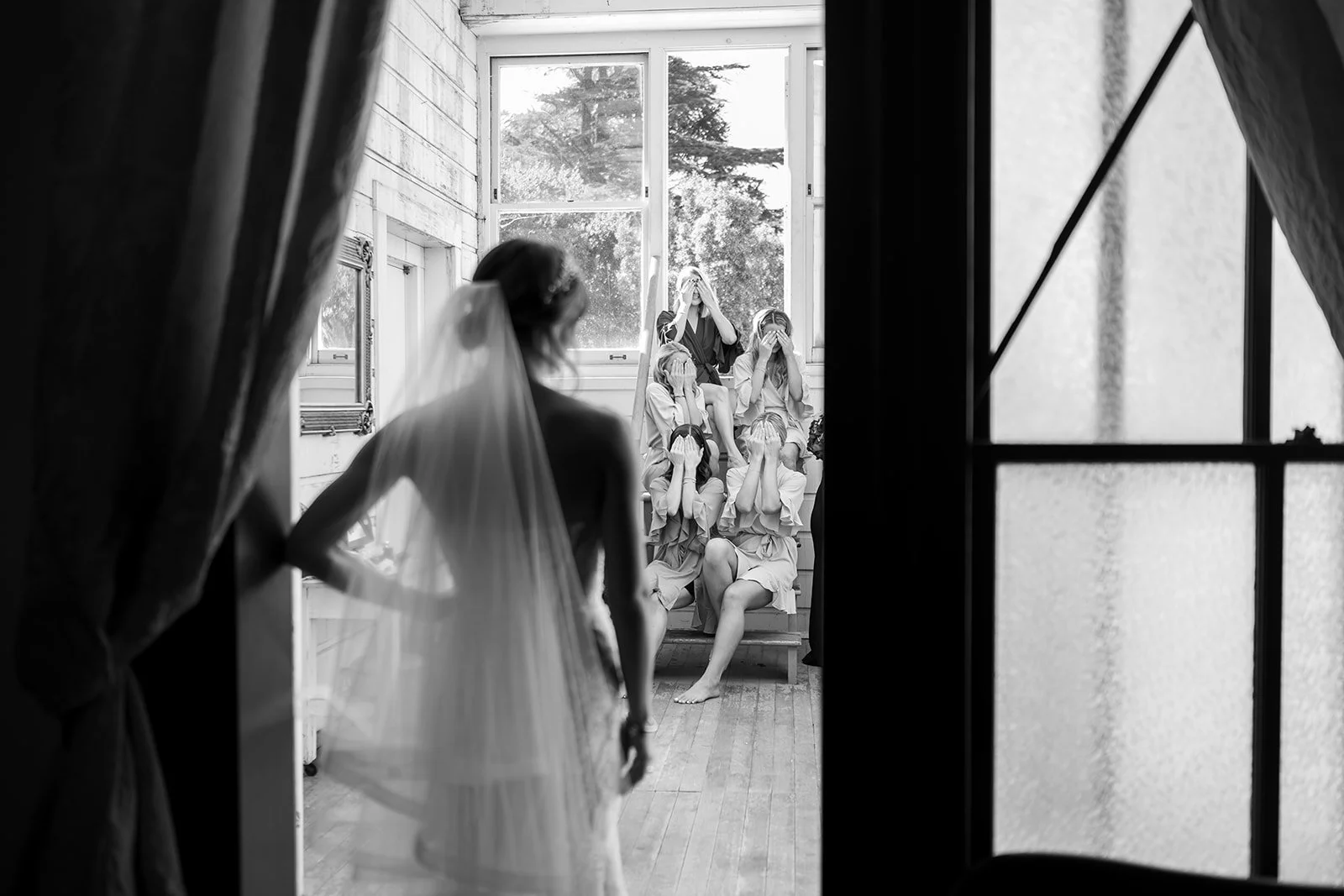 a black and white photo of a bride doing a first look with her bridesmaids