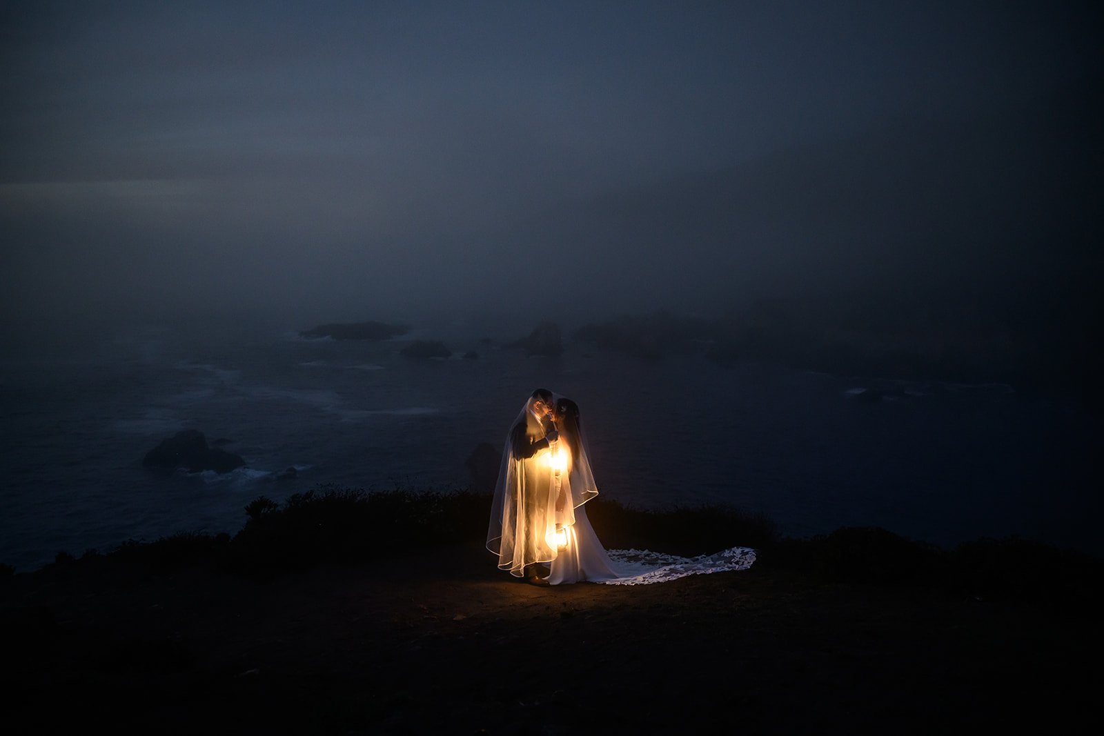 bride and groom under a veil with lanterns at night