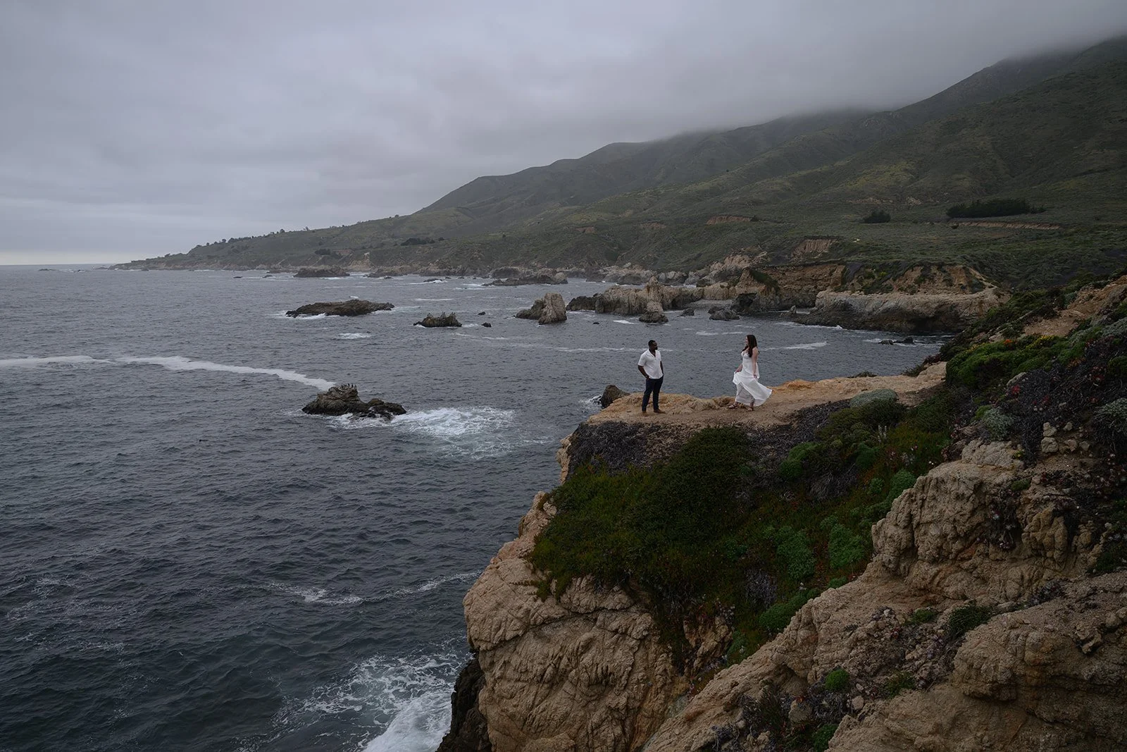 a bride and groom on a cliffside in Big Sur on their wedding day