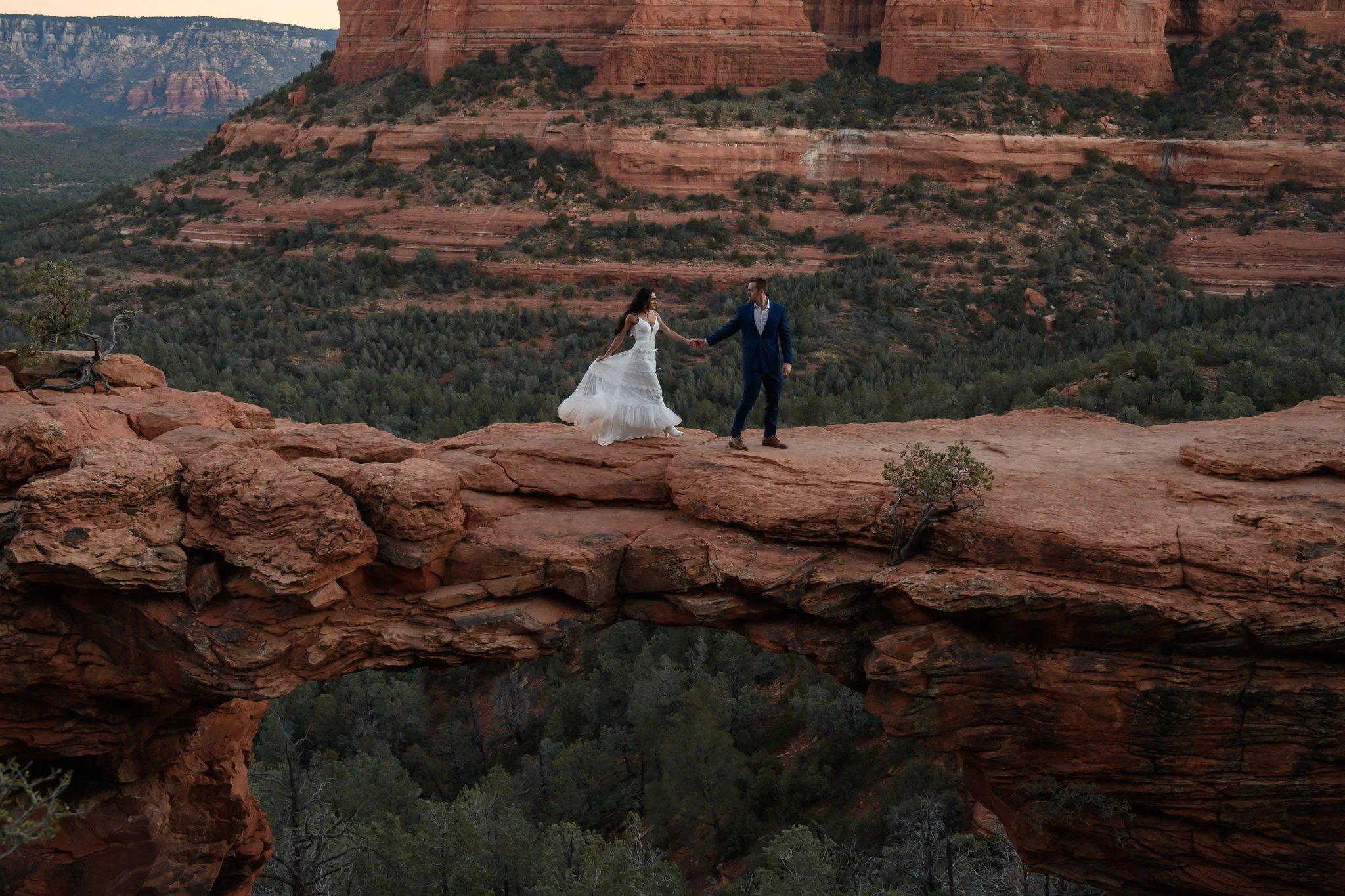 an adventure elopement in Sedona with a bride and a groom walking across devil's bridge