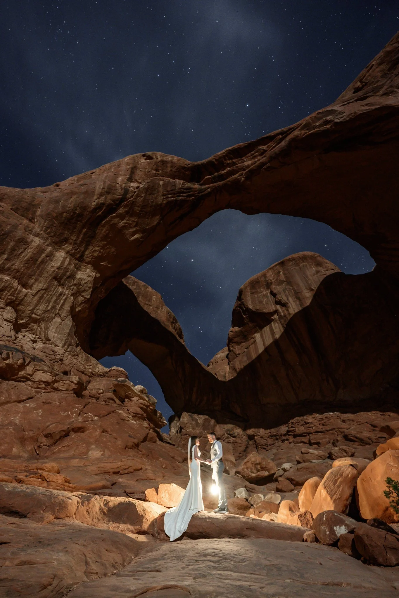 bride and groom at night with lanterns in Arches National Park with a starry sky