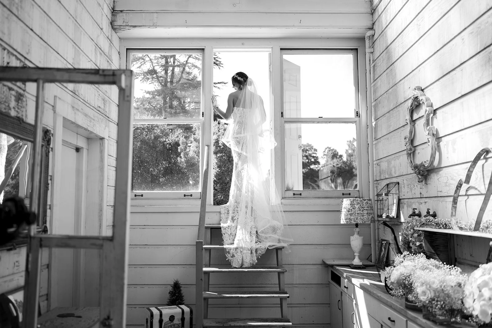 A bride standing in a doorway on her wedding day in black and white