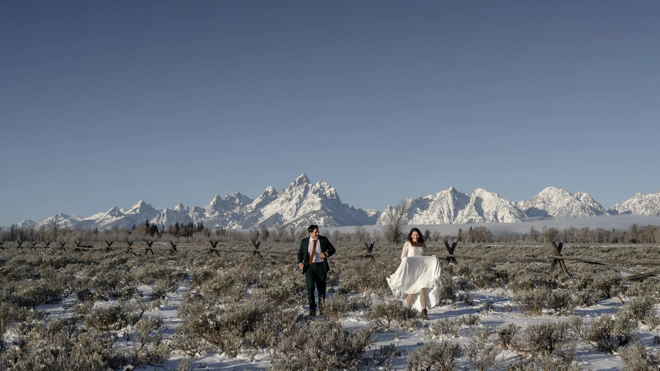 a bride and groom running through the snow in the Grand Tetons on their wedding day