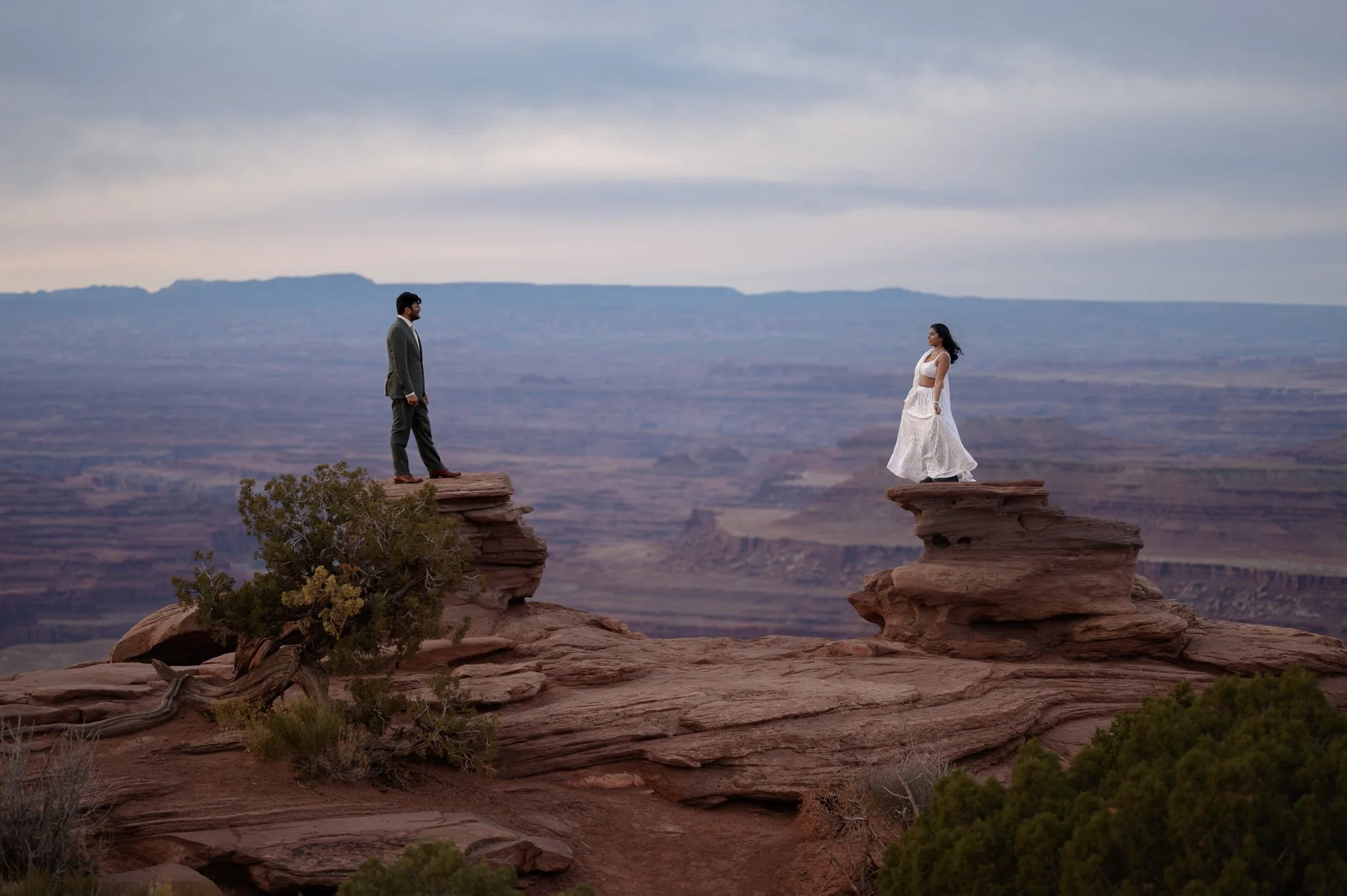 a couple standing on rocks facing each other in Moab, Utah on their wedding day