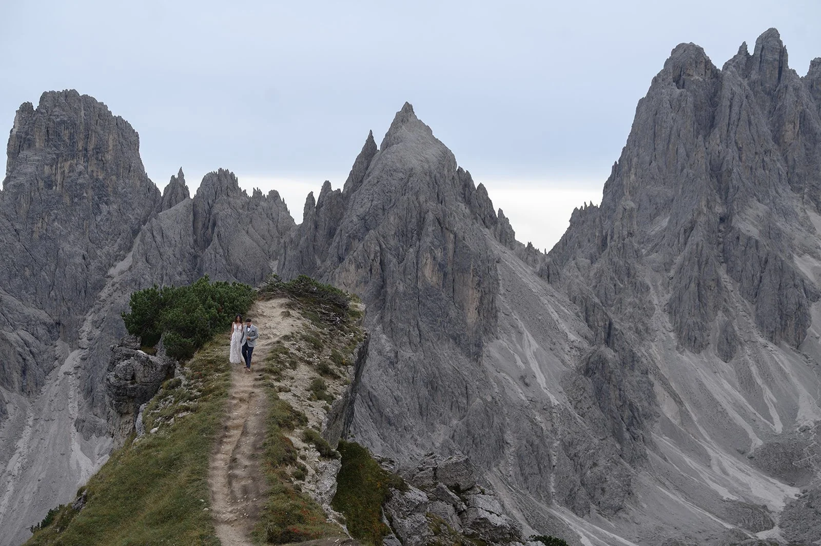 wedding in the Dolomites in Italy with the Bride and groom walking down a path with the mountains behind them